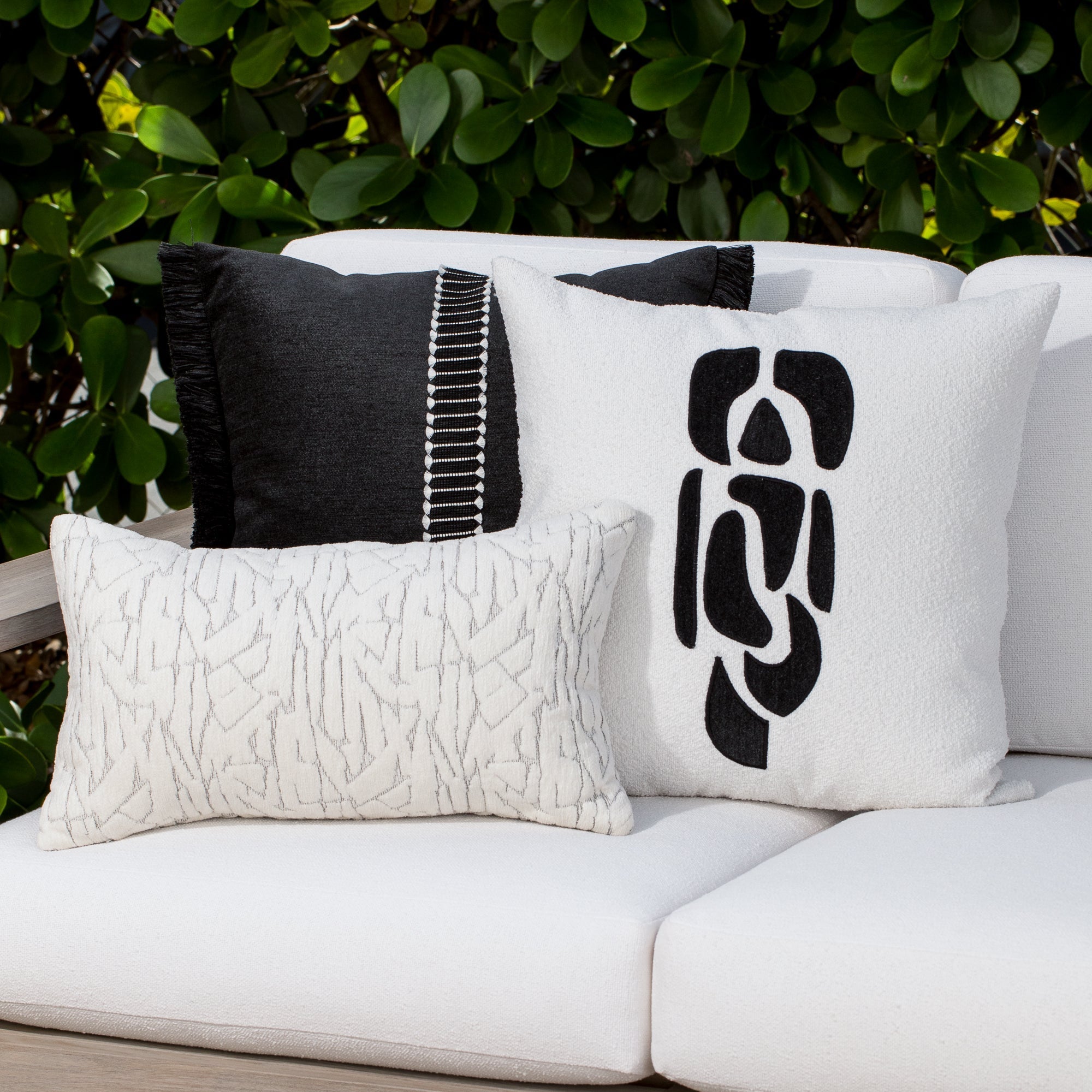 Luxury black and ivory textured woven decorative pillows on a woven outdoor sofa, featuring solution dyed performance fibers for hospitality and commercial spaces