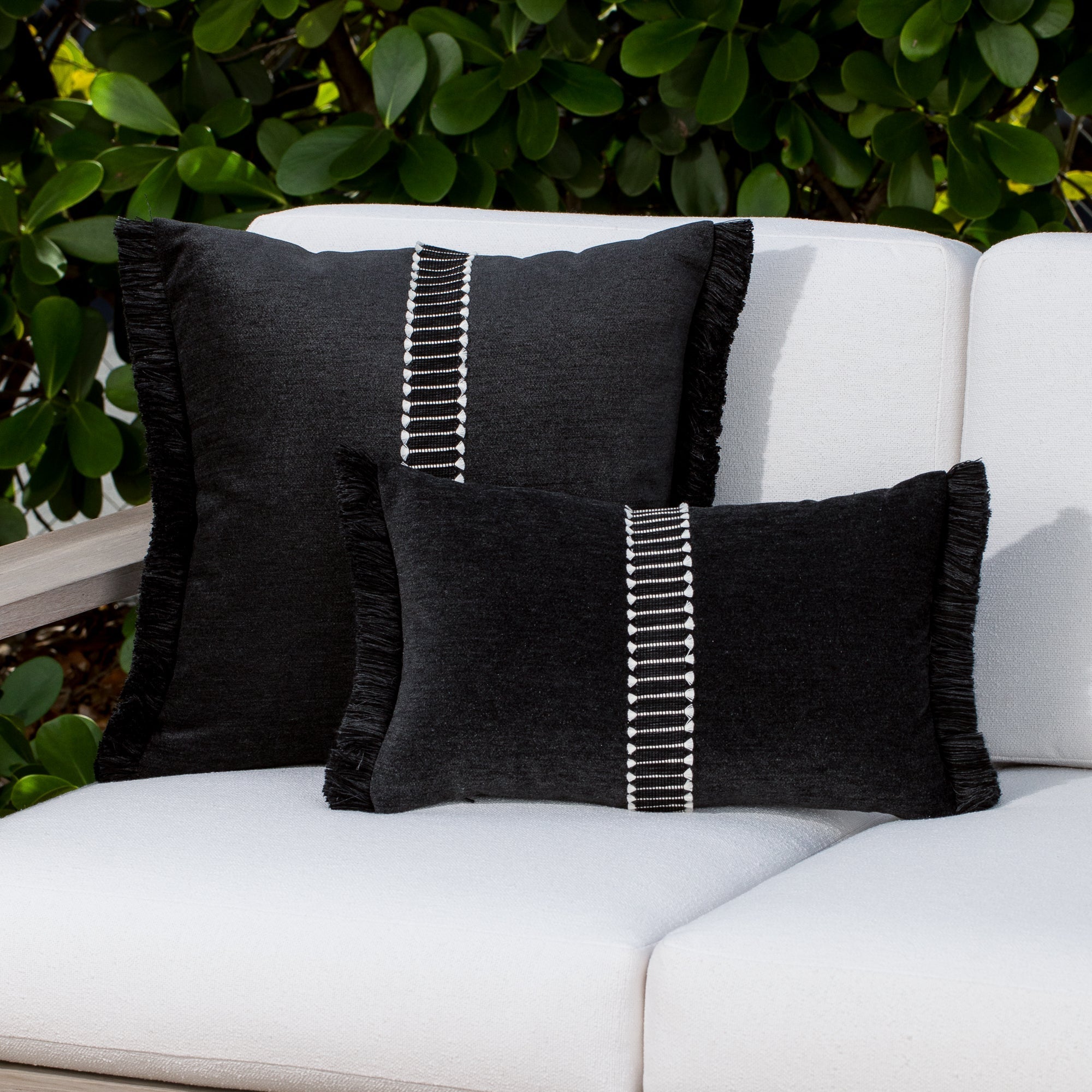 Luxury black velvet textured woven decorative pillows on a woven outdoor sofa, featuring solution dyed performance fibers for hospitality and commercial spaces