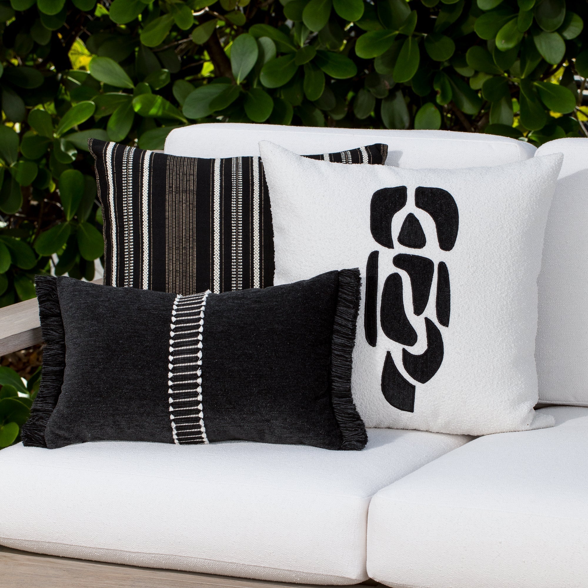 Luxury black velvet textured woven decorative pillows on a woven outdoor sofa, featuring solution dyed performance fibers for hospitality and commercial spaces