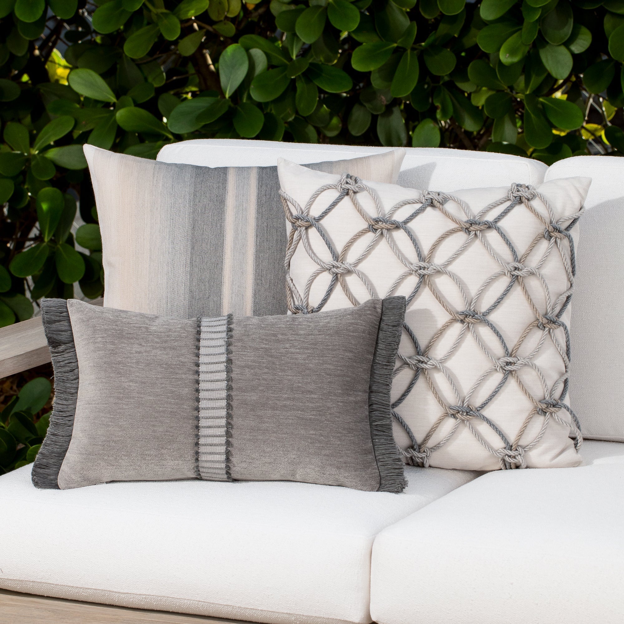 Luxury pewter velvet textured woven decorative pillows on a woven outdoor sofa, featuring solution dyed performance fibers for hospitality and commercial spaces