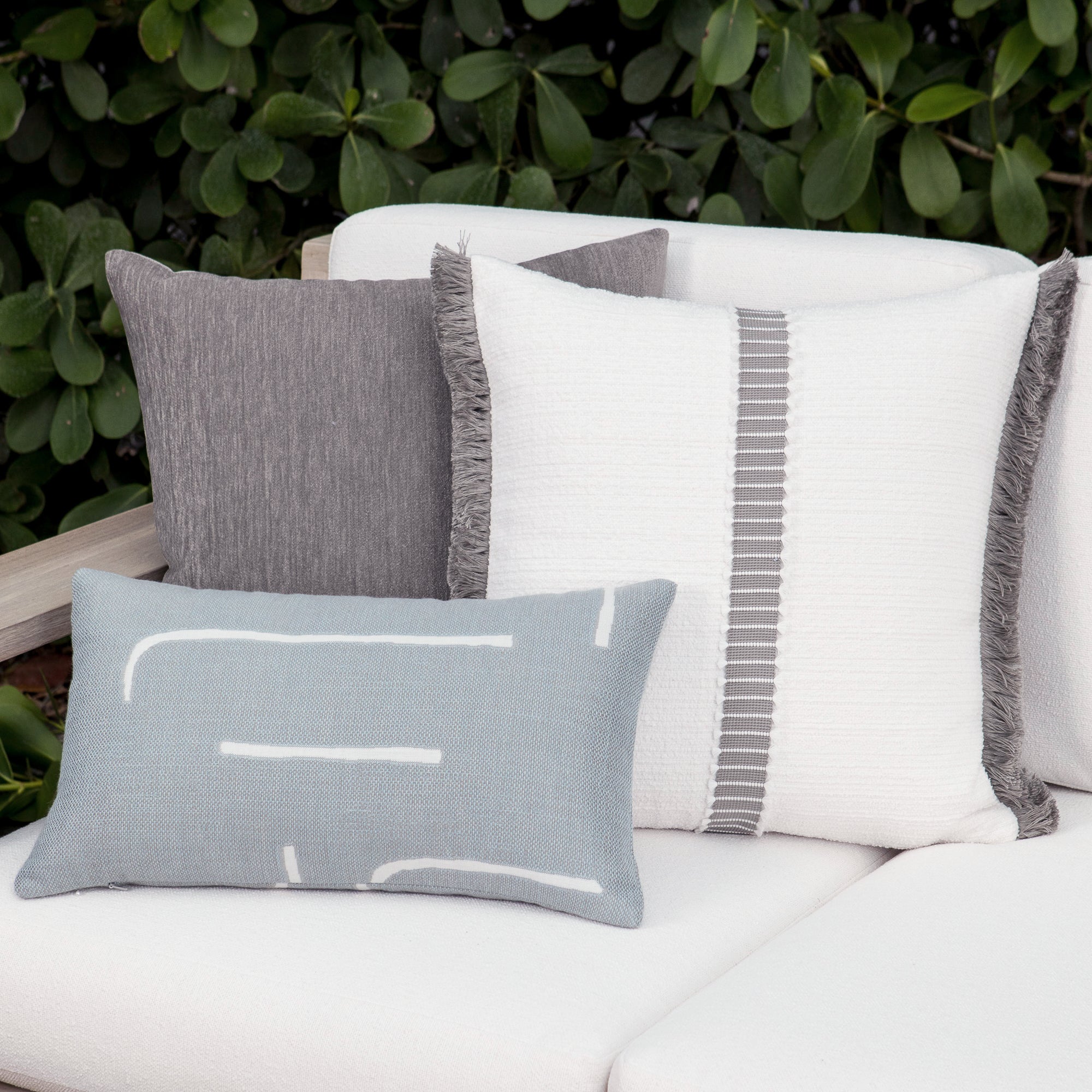 Luxury white textured woven decorative pillows on a woven outdoor sofa, featuring solution dyed performance fibers for hospitality and commercial spaces