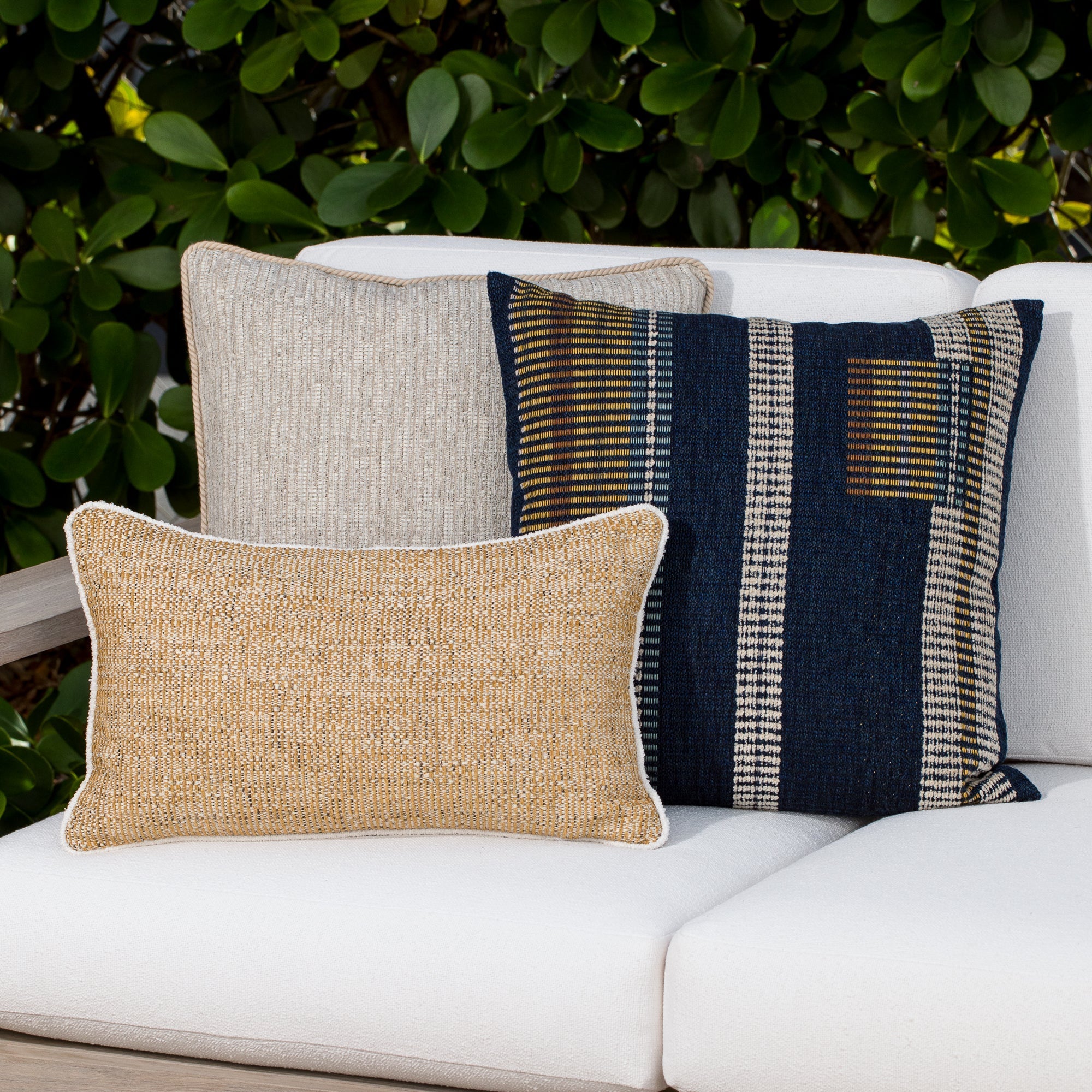Luxury gold geometric patterned accent pillow on an indoor and outdoor sofa, featuring solution dyed performance fibers for hospitality and commercial spaces