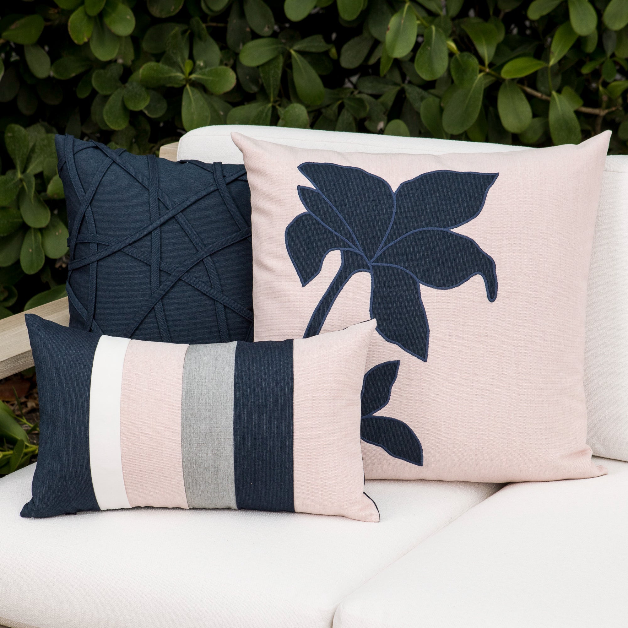 Luxury indigo, pink and gray embroidered throw pillow on a outdoor sofa, featuring soft touch performance weave for residential and commercial interiors