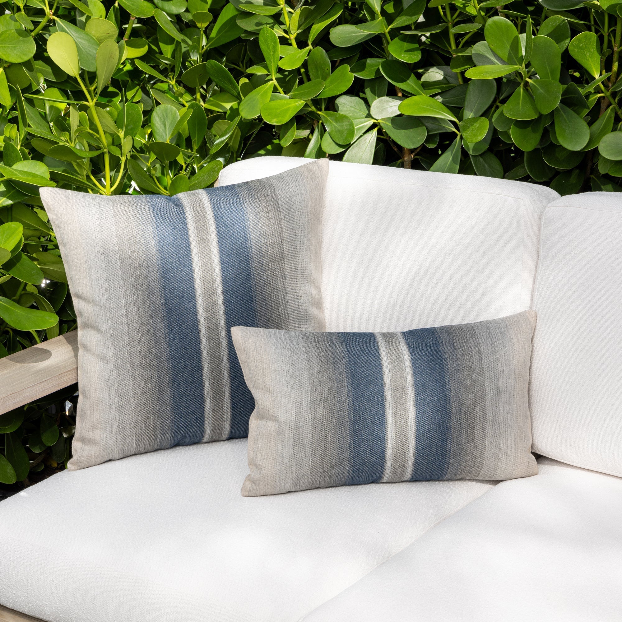 Luxury slate blue ombre striped throw pillow on a outdoor sofa, featuring easy clean performance fabric for luxury hotel and resort design by Elaine Smith