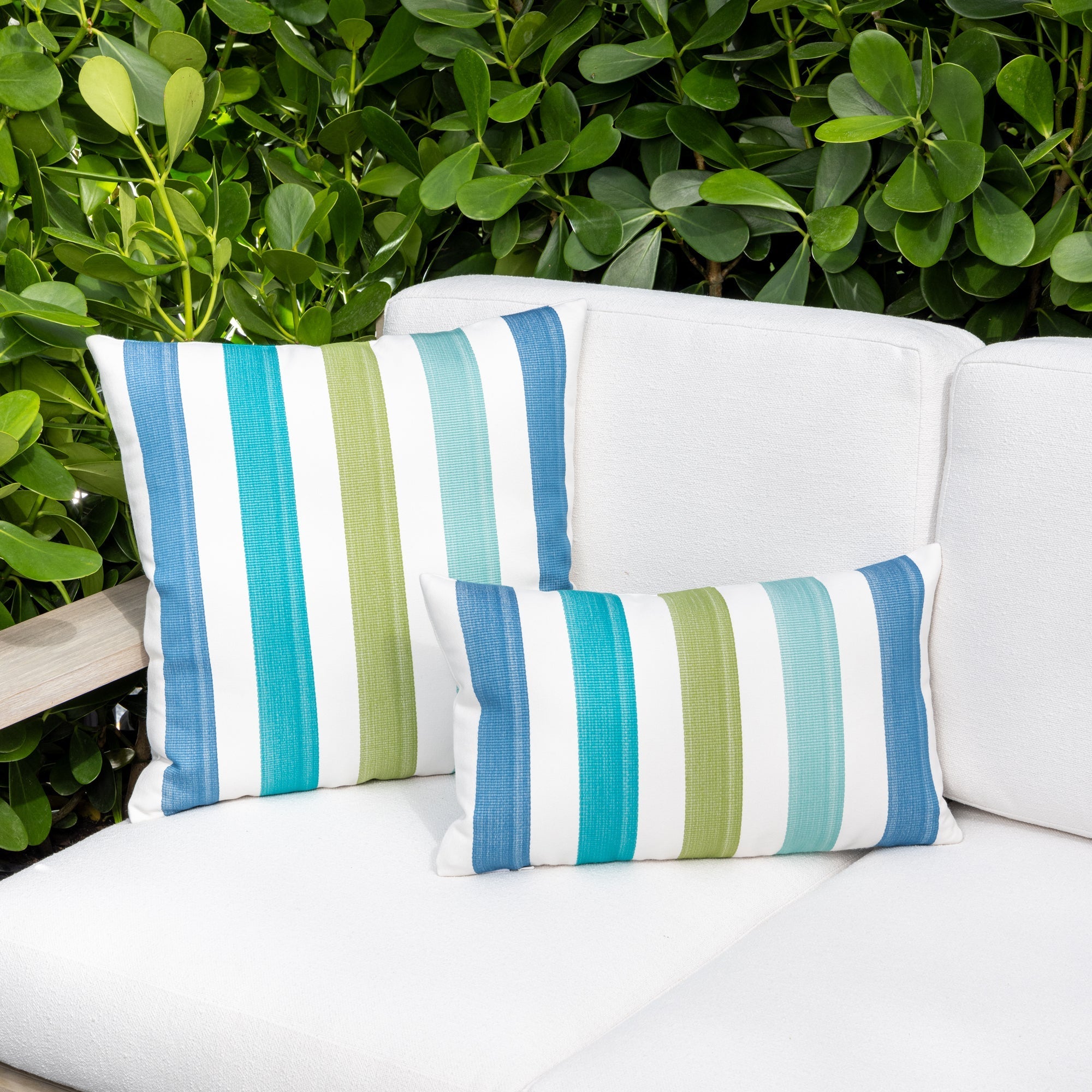 Luxury green and blue striped accent pillow on an outdoor sofa, featuring soft touch performance weave for residential and commercial interiors