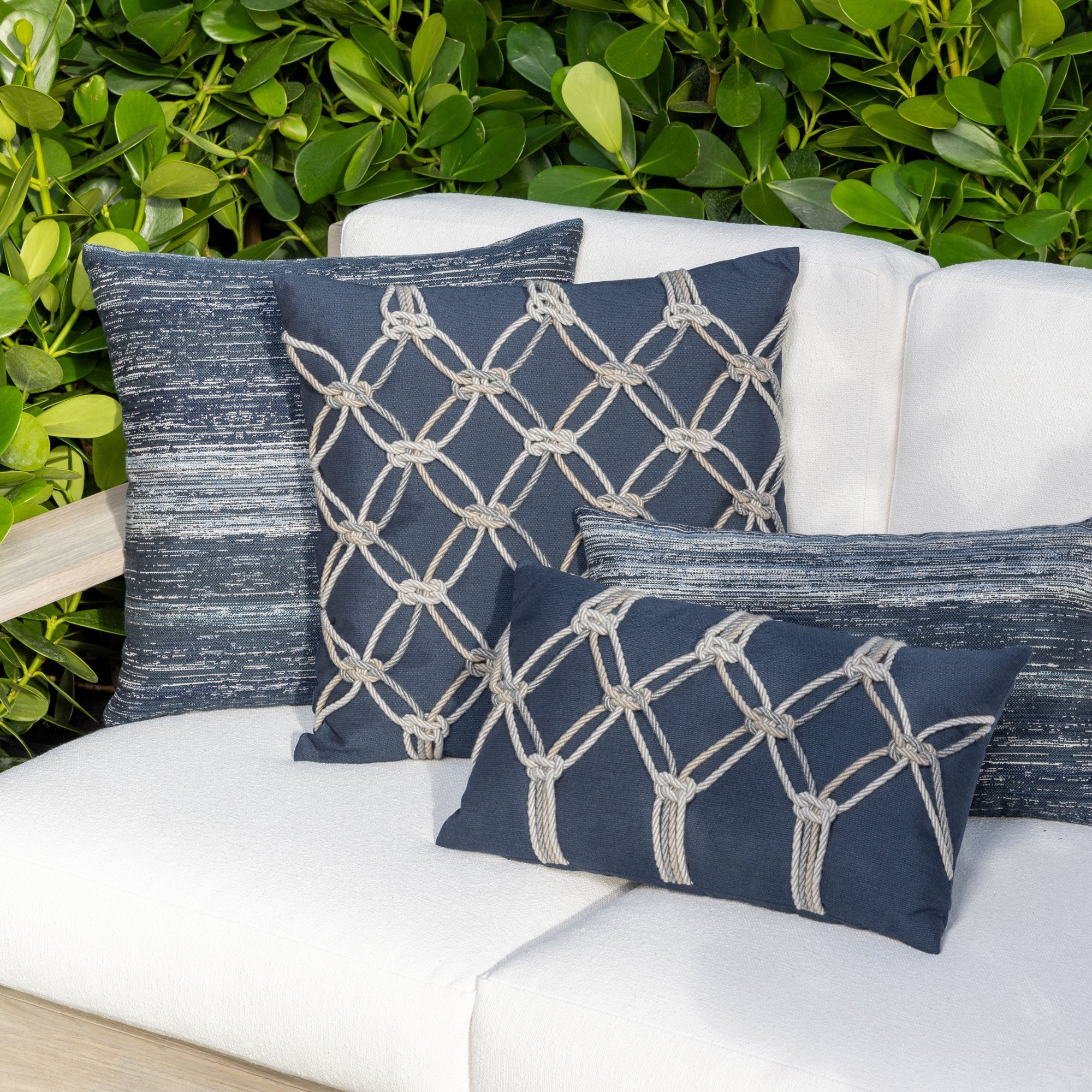 Outdoor image of denim blue pillows with hand appliqued rope detailing in multi colors for indoor and outdoor use.