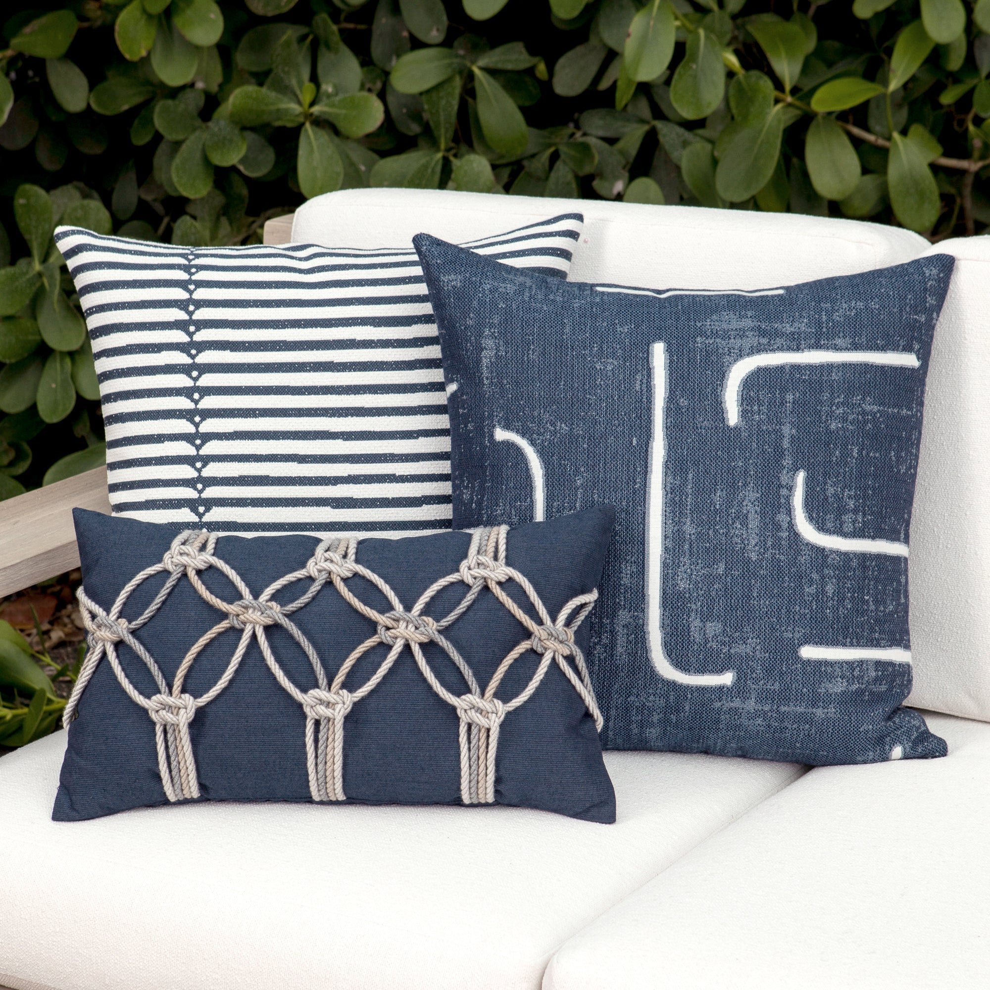 Outdoor image of denim blue pillows with hand appliqued rope detailing in multi colors for indoor and outdoor use.