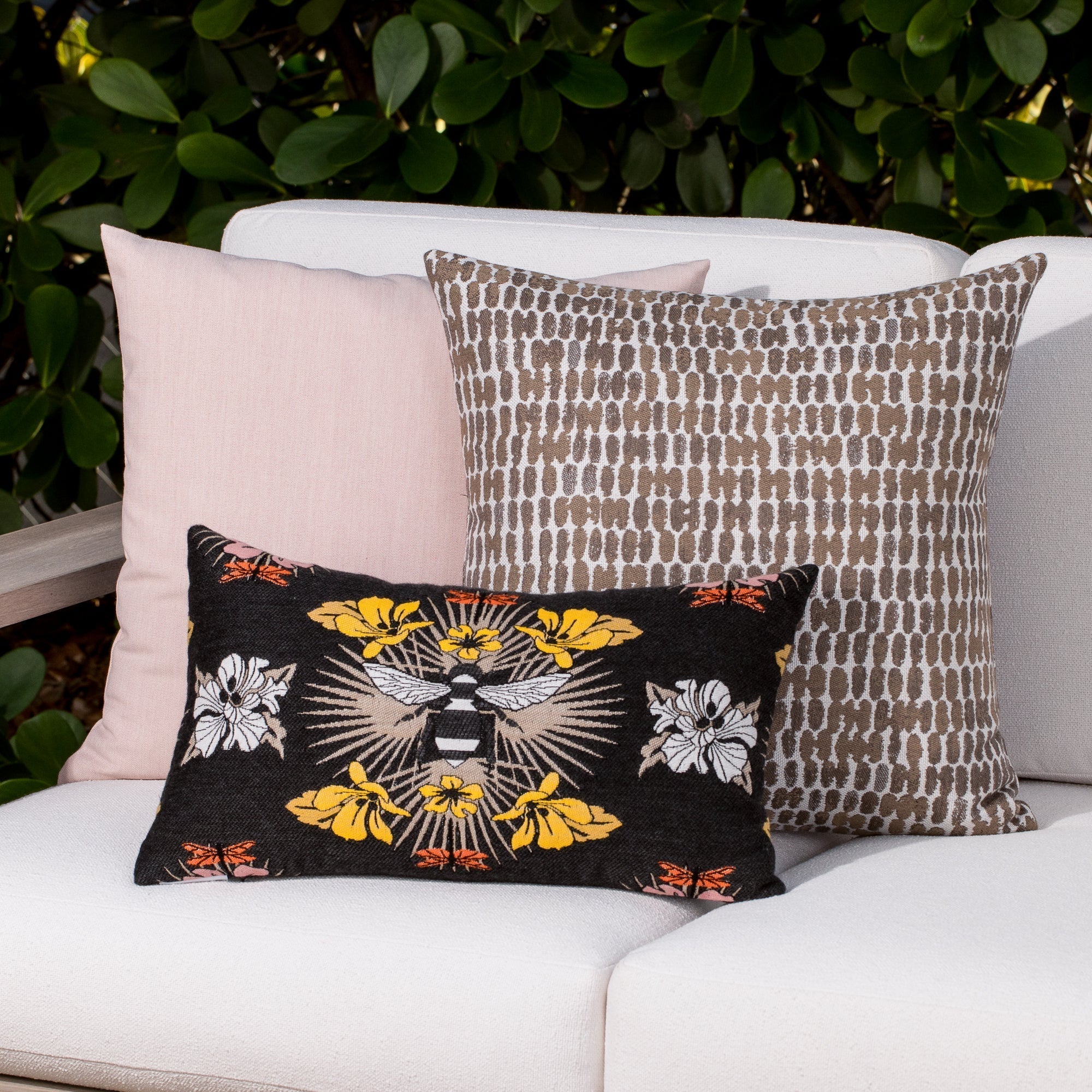 Luxury pink, and taupe and charcoal botanical patterned accent cushion on an outdoor sofa, featuring soft touch performance weave for residential and commercial interiors