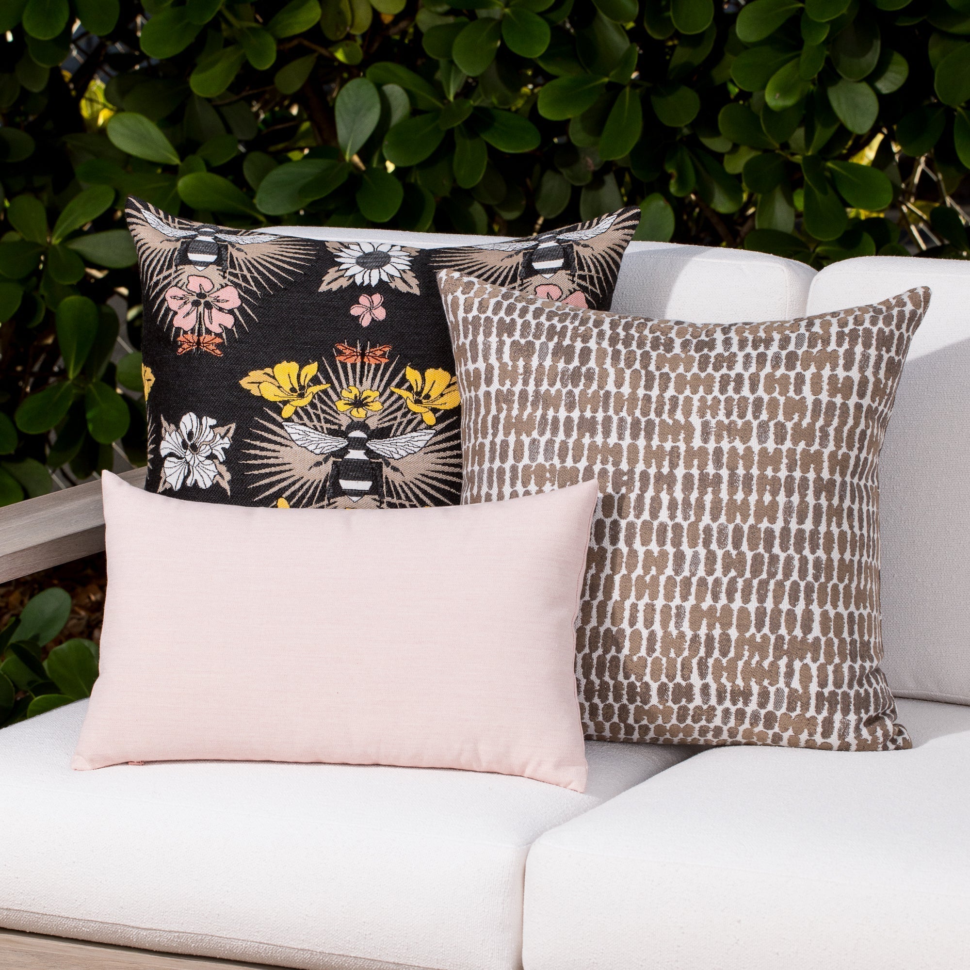 Luxury pink, and taupe and charcoal botanical patterned accent cushion on an outdoor sofa, featuring soft touch performance weave for residential and commercial interiors