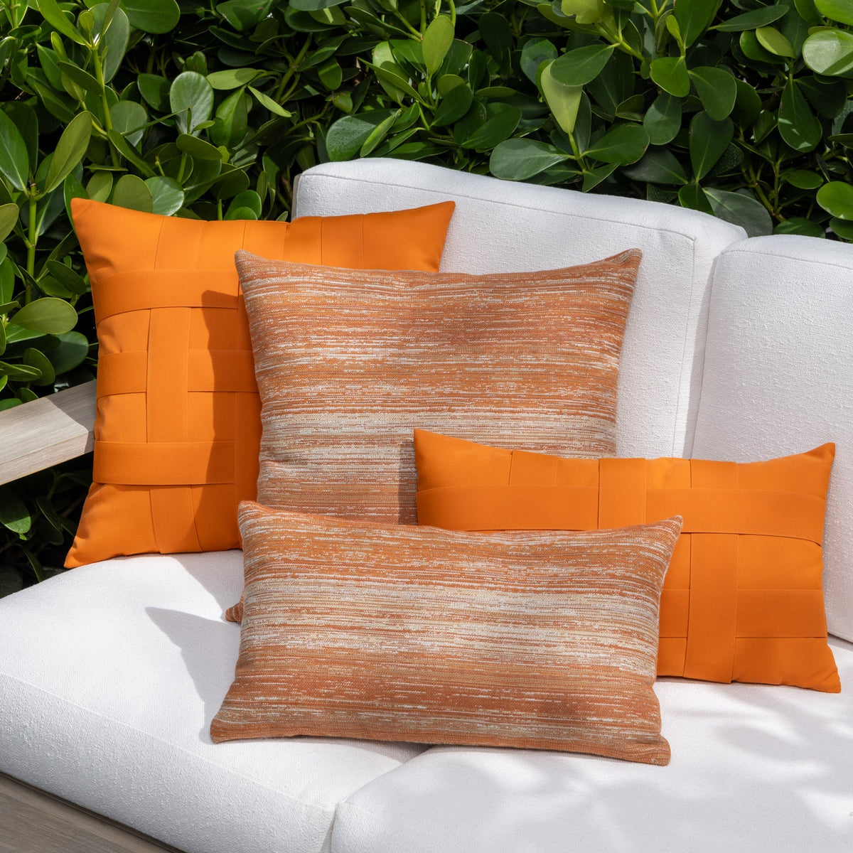 Luxury orange basketweave throw pillow on a outdoor sofa, featuring UV and fade resistant fabric to complete indoor and outdoor decor
