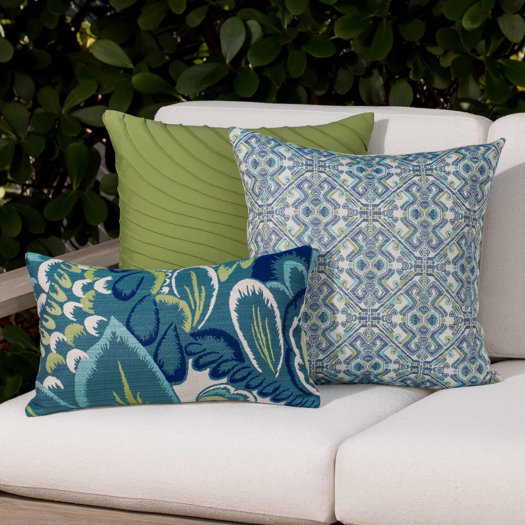 Luxury green and blue floral  and solid accent pillow on an outdoor sofa, featuring soft touch performance weave for residential and commercial interiors