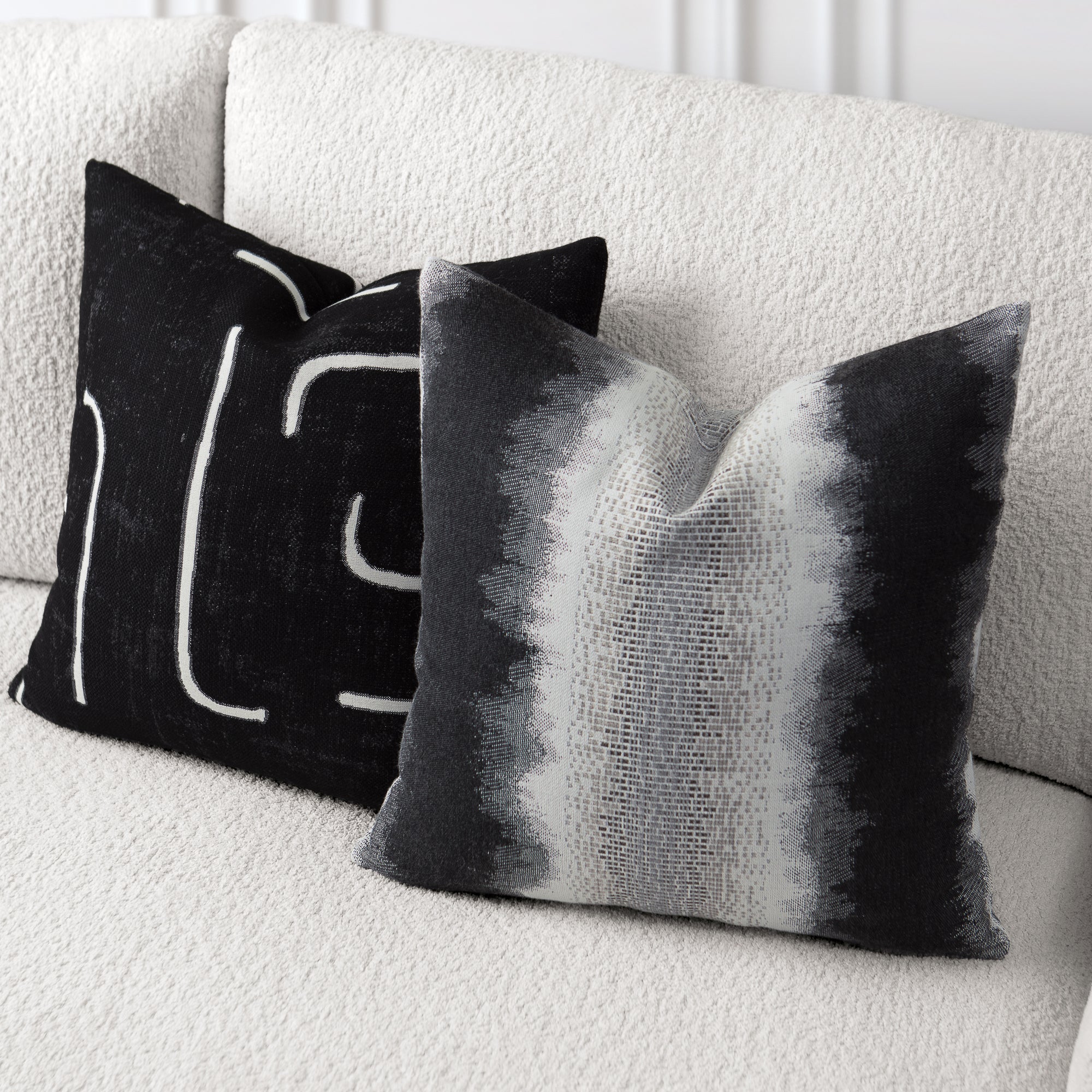 Two decorative pillows on a white couch, one with black and white abstract pattern and the other with gradient black to gray.- outdoor safe by Elaine Smith