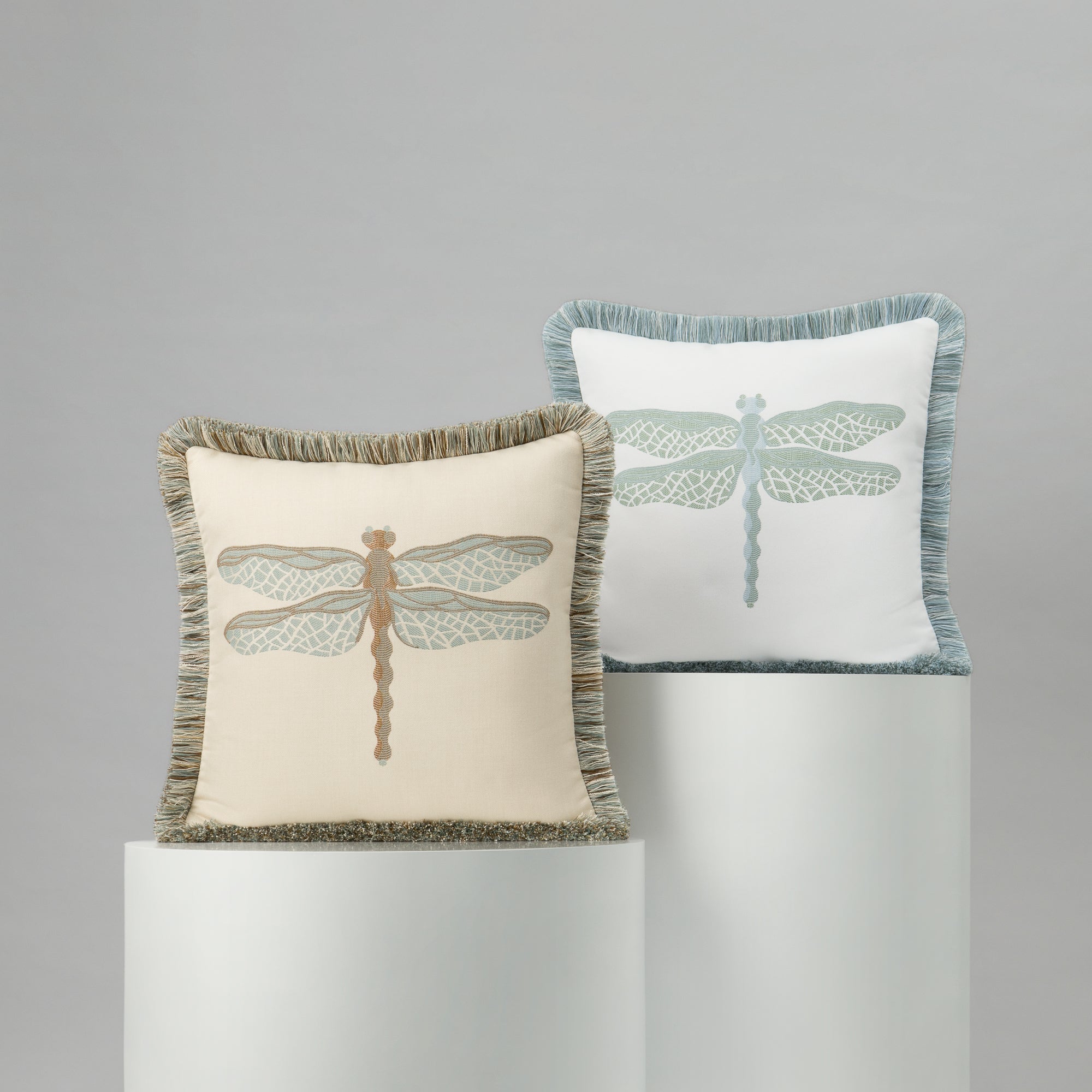 Two decorative pillows with dragonfly designs on a gray background