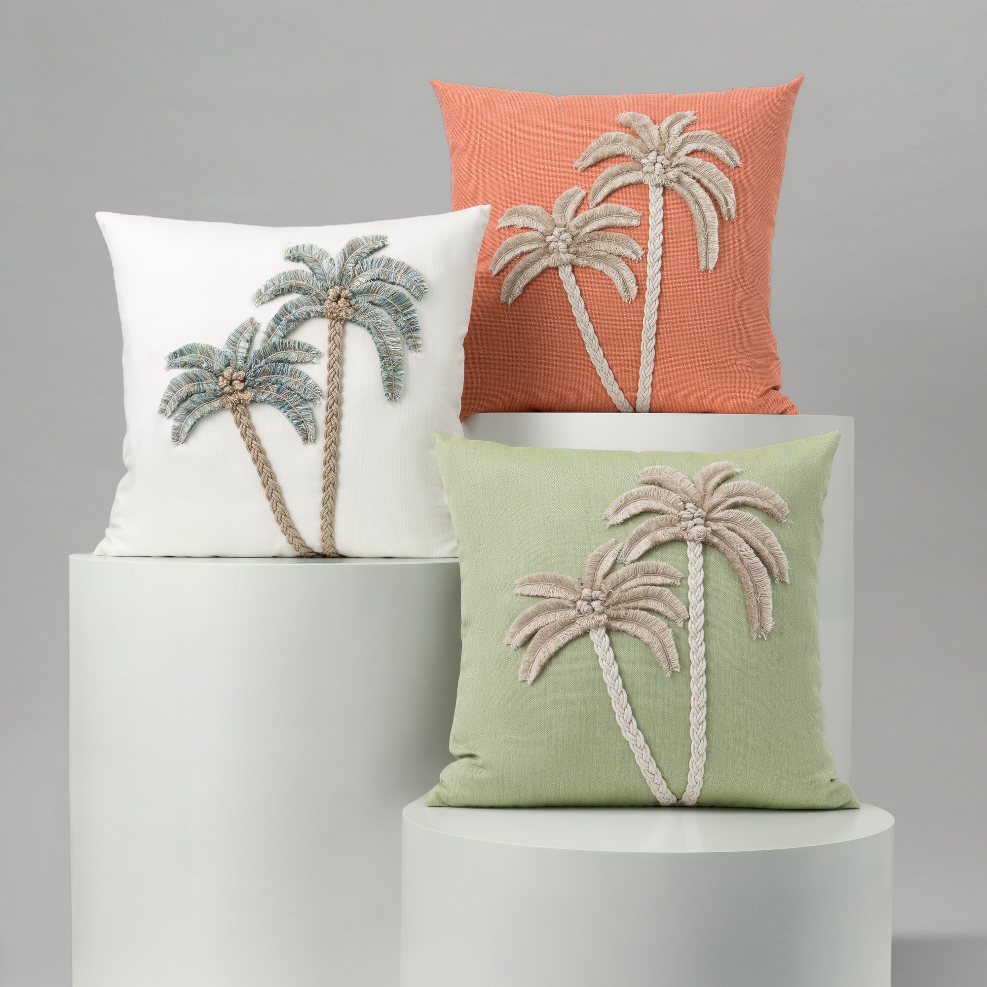 Three decorative pillows with palm tree designs on a gray background