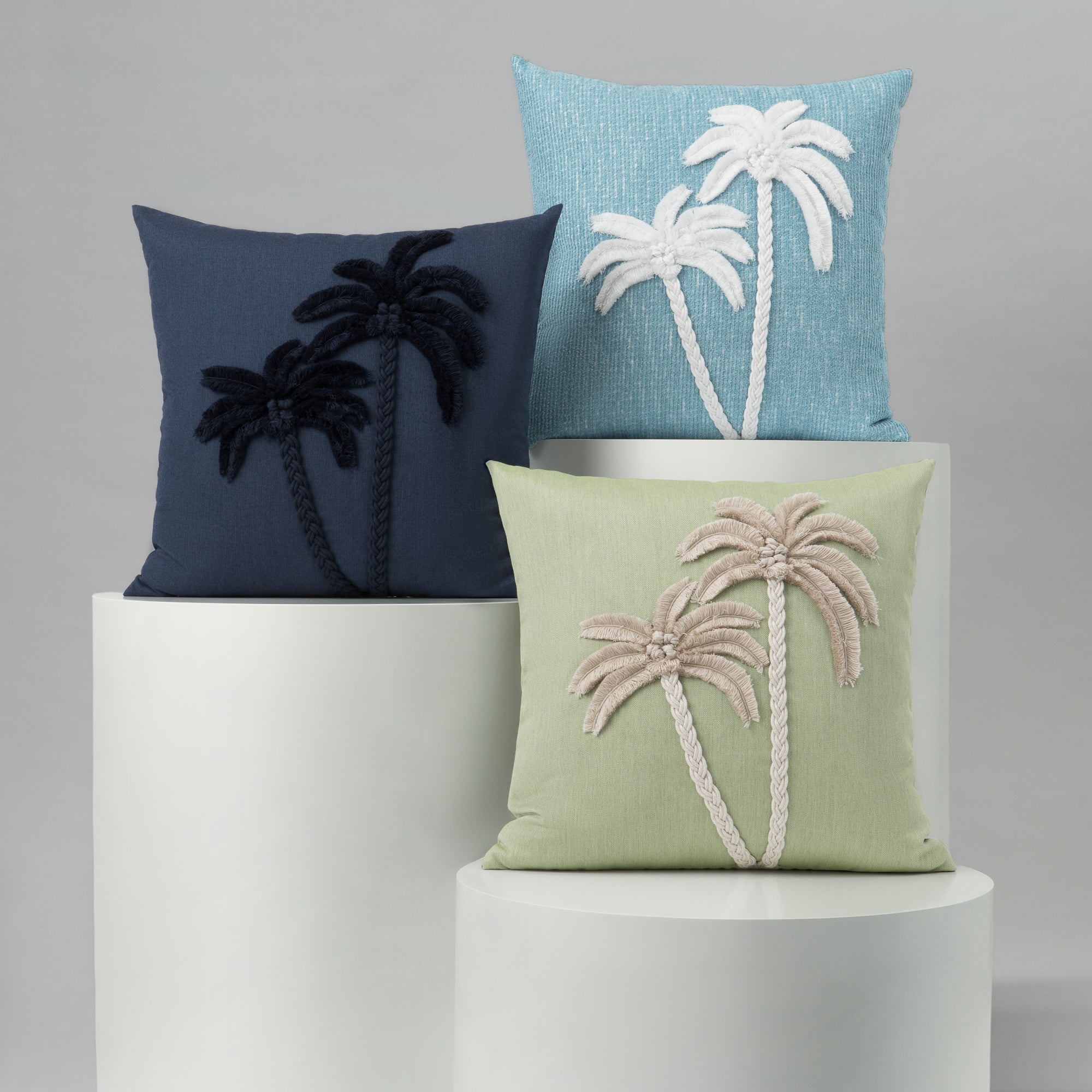 Three decorative pillows with palm tree designs on a gray background