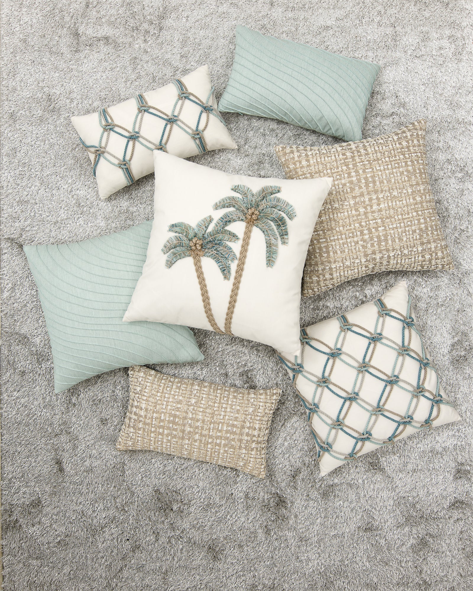 Collection of decorative pillows with palm tree design on a textured surface