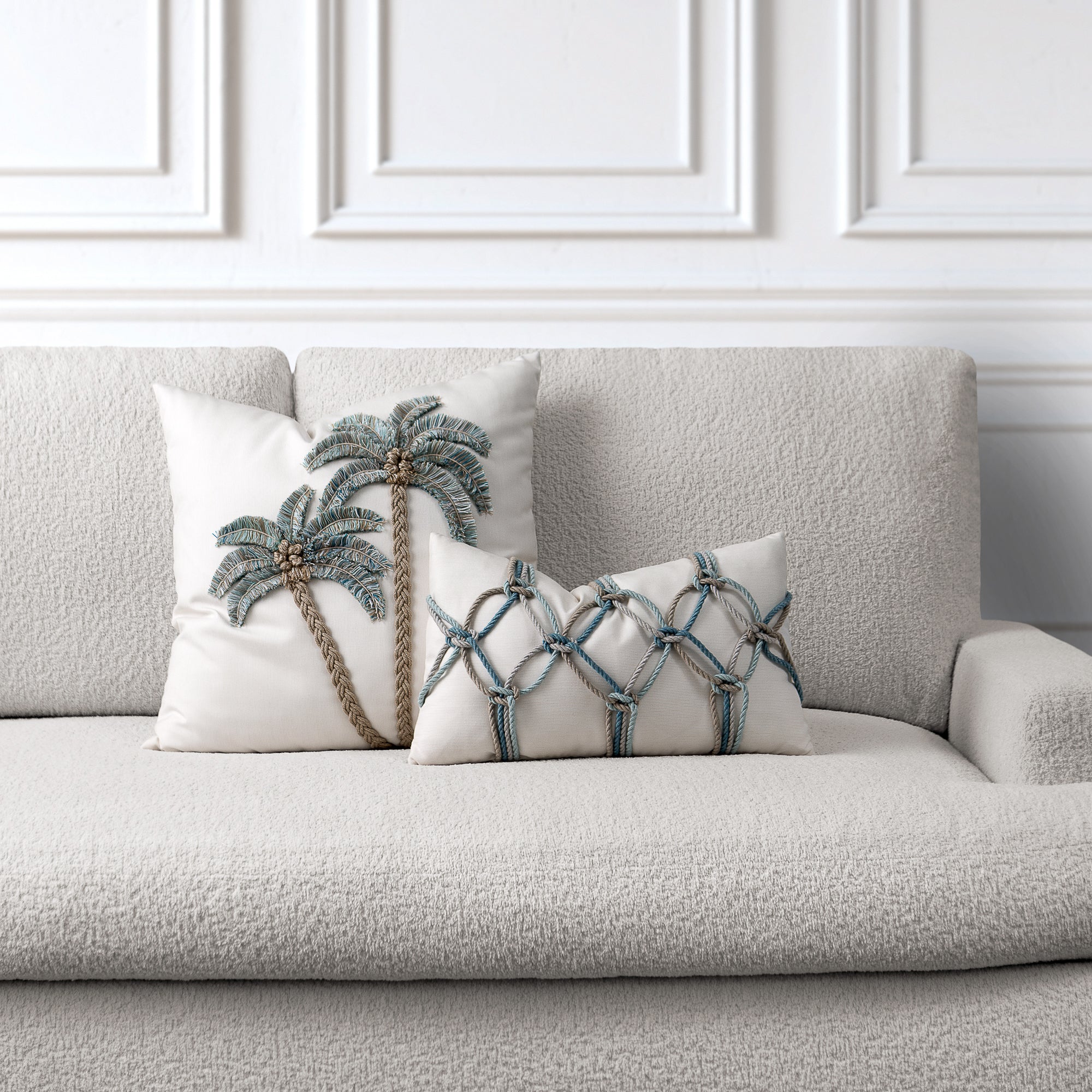 Decorative pillows with palm tree design on a gray sofa against a white wall.