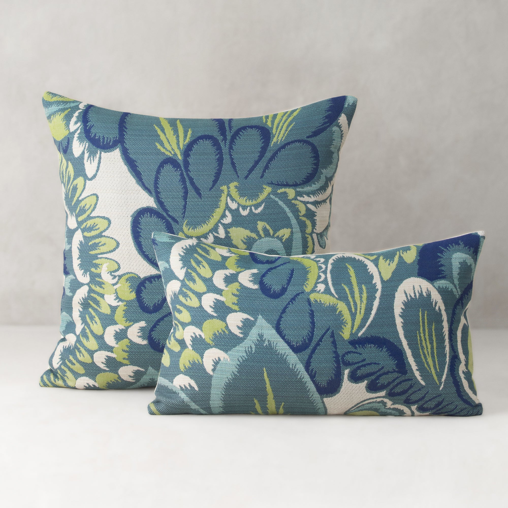 Two decorative pillows with a floral pattern on a neutral background