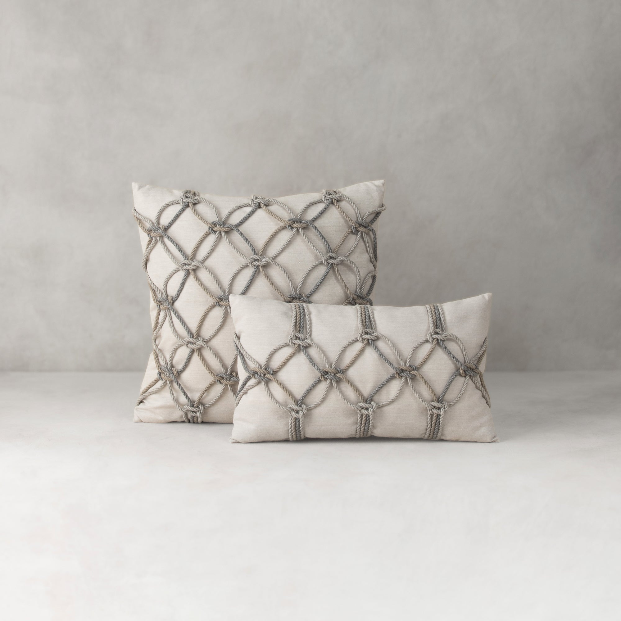 Two decorative pillows with geometric patterns on a neutral background
