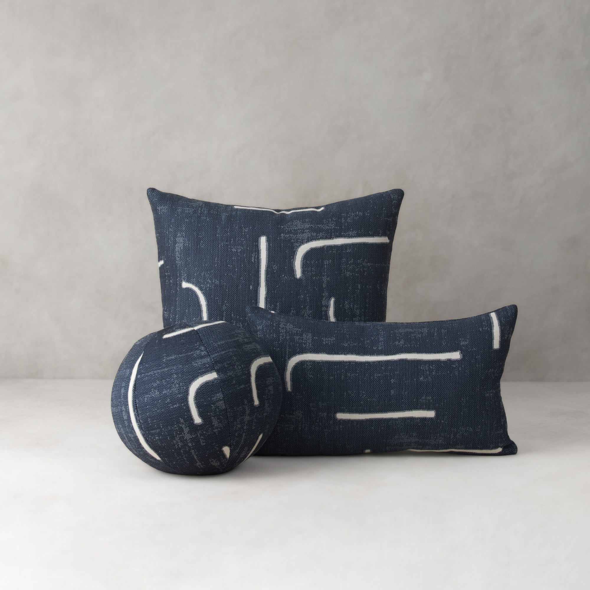 Two blue pillows with white abstract patterns on a gray background