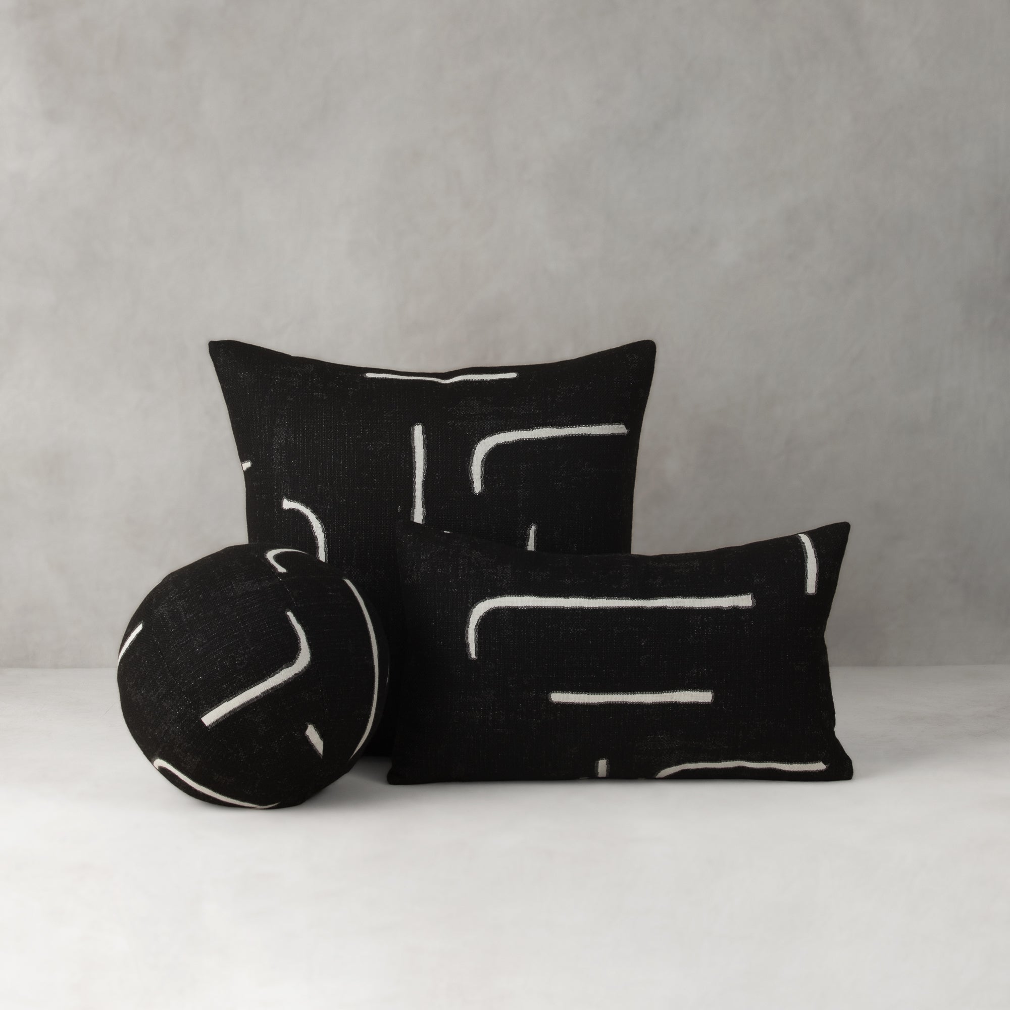 Black pillows with white patterns on a gray background- outdoor safe by Elaine Smith