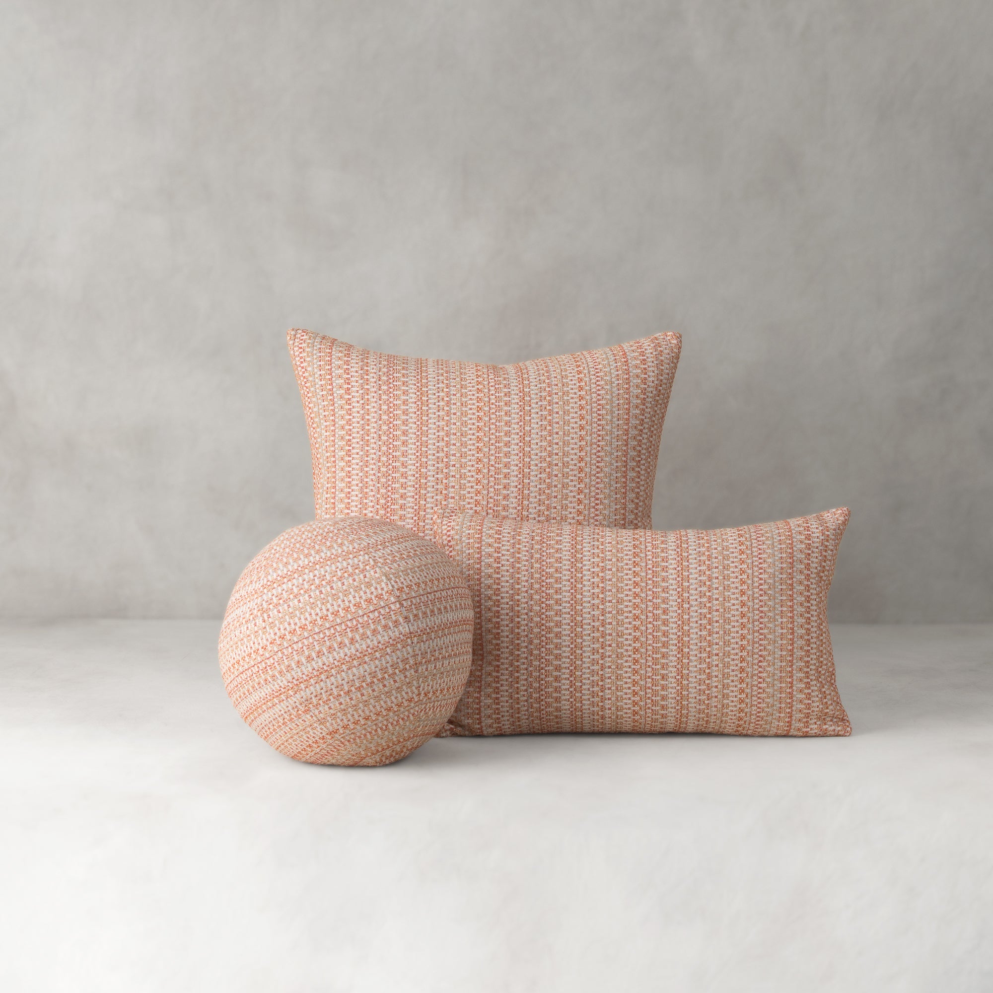 Three woven pillows in a pattern on a plain background