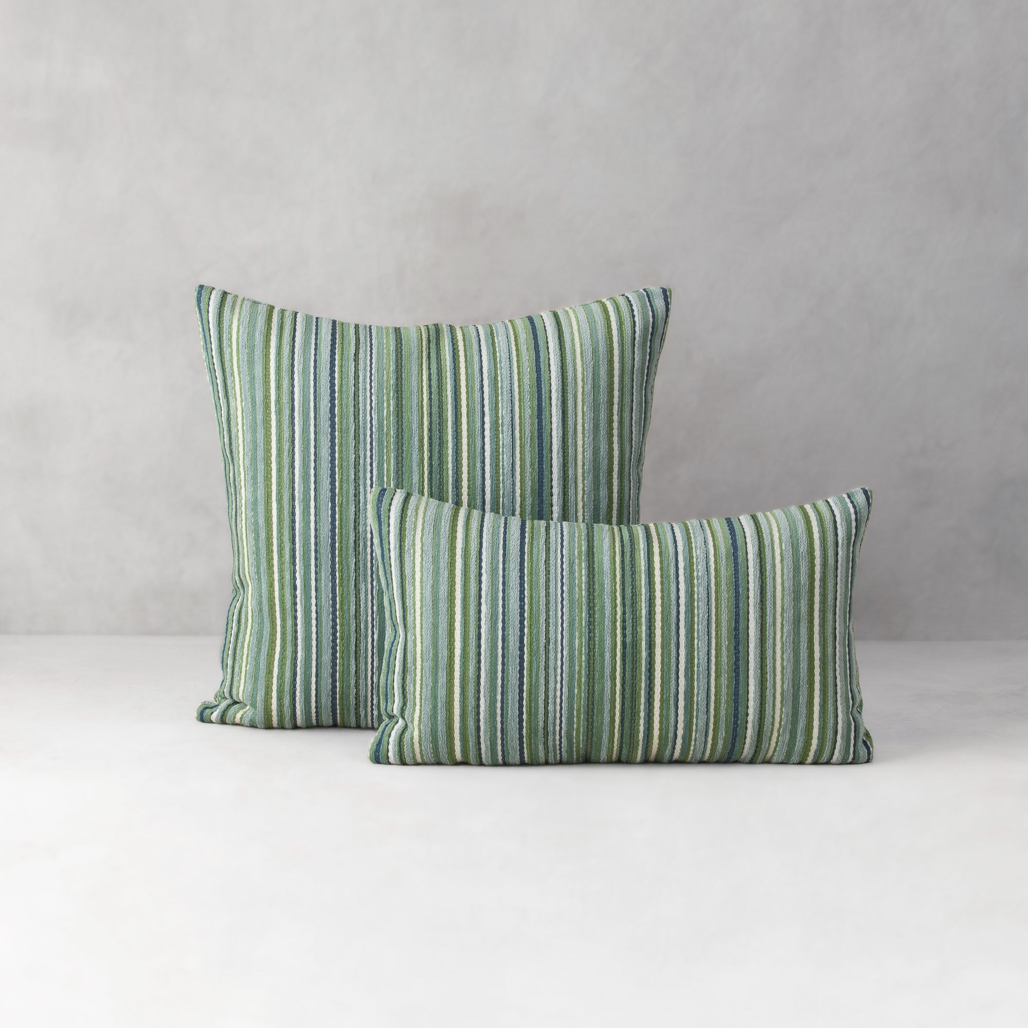 Two green striped pillows on a neutral background