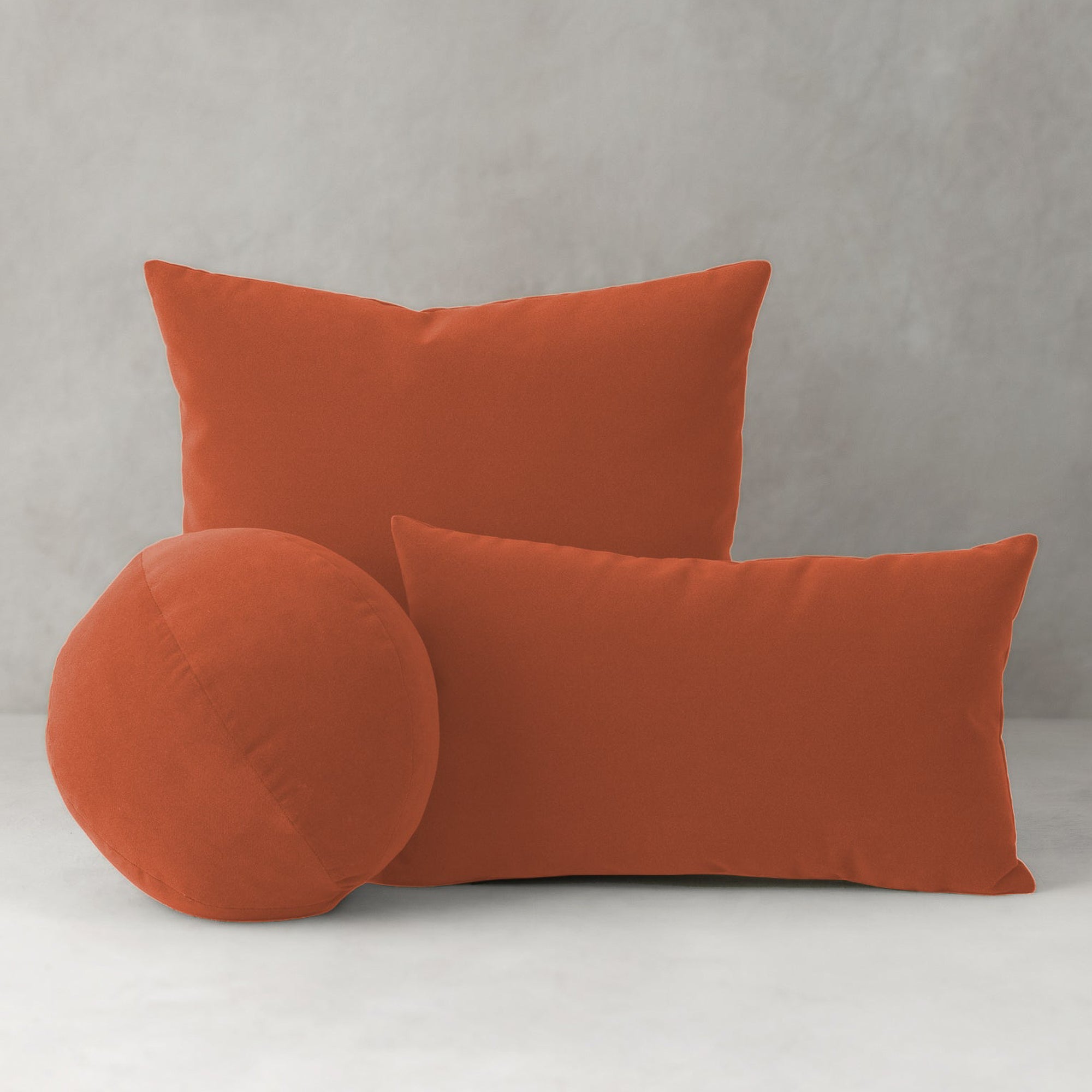Three papaya pillows of different shapes on a light gray background