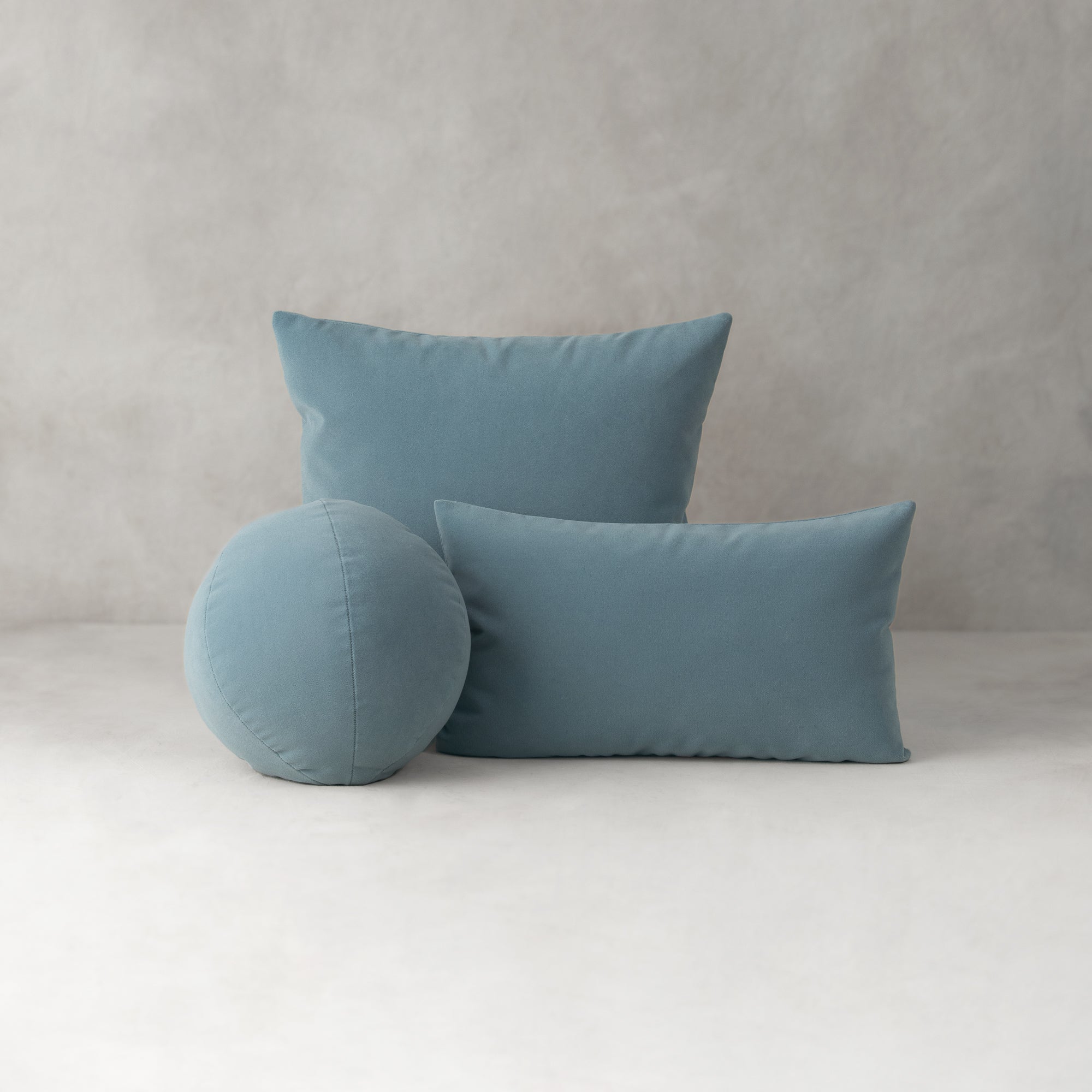 Three blue pillows of different shapes on a light gray background
