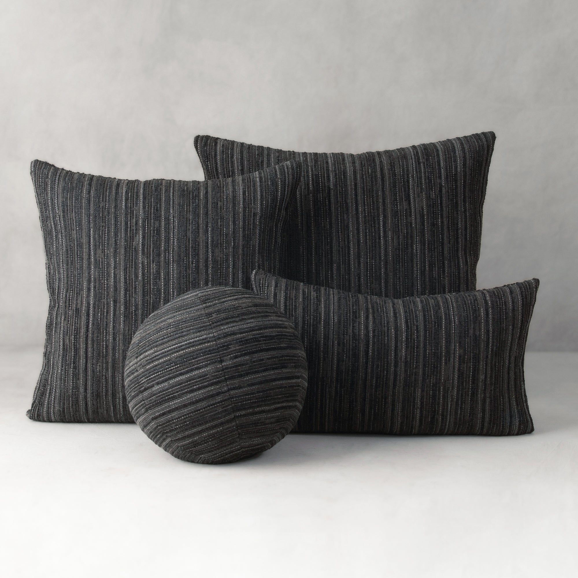 Set of black striped cushions on a white surface with a gray background