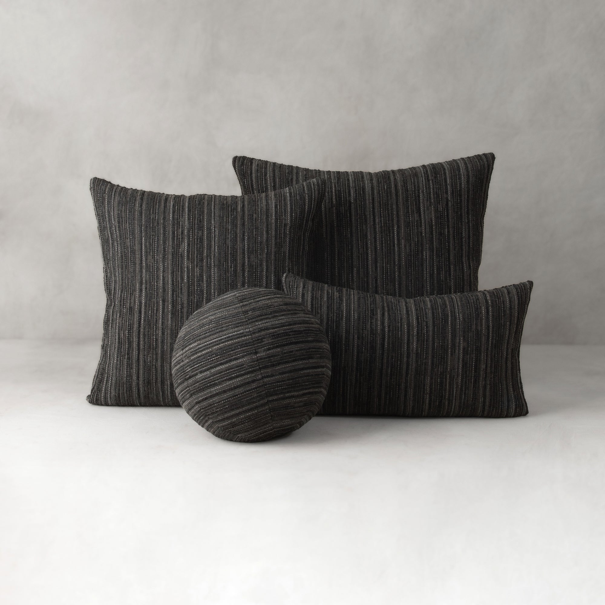 Set of black striped cushions on a white surface with a gray background
