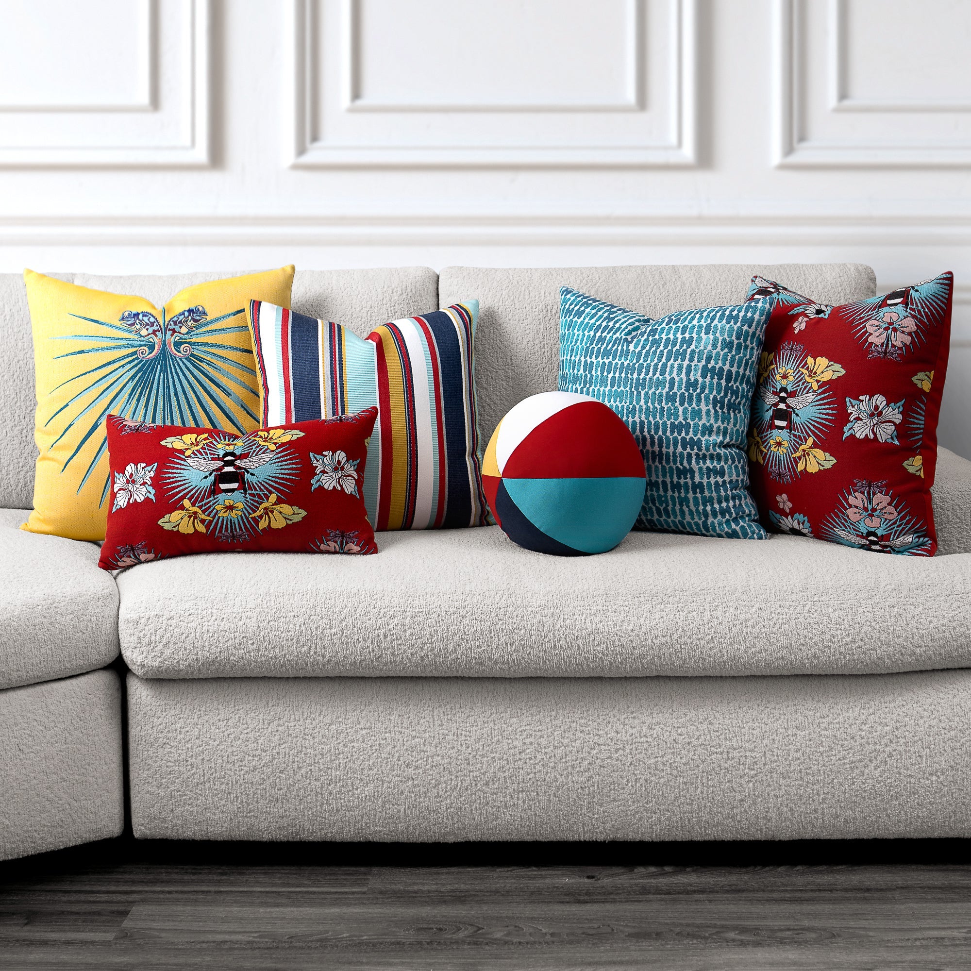 Colorful pillows on a gray sofa against a white wall.