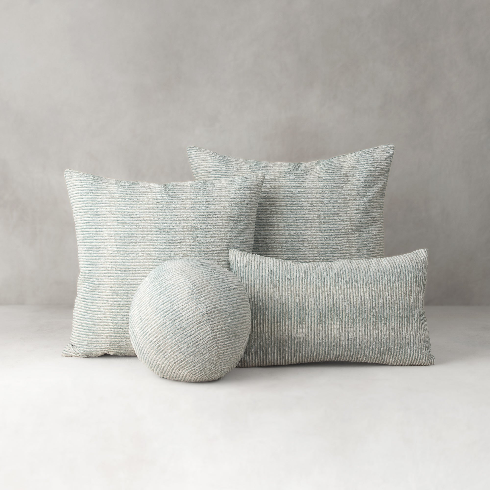 Set of striped cushions and a round pillow on a neutral background