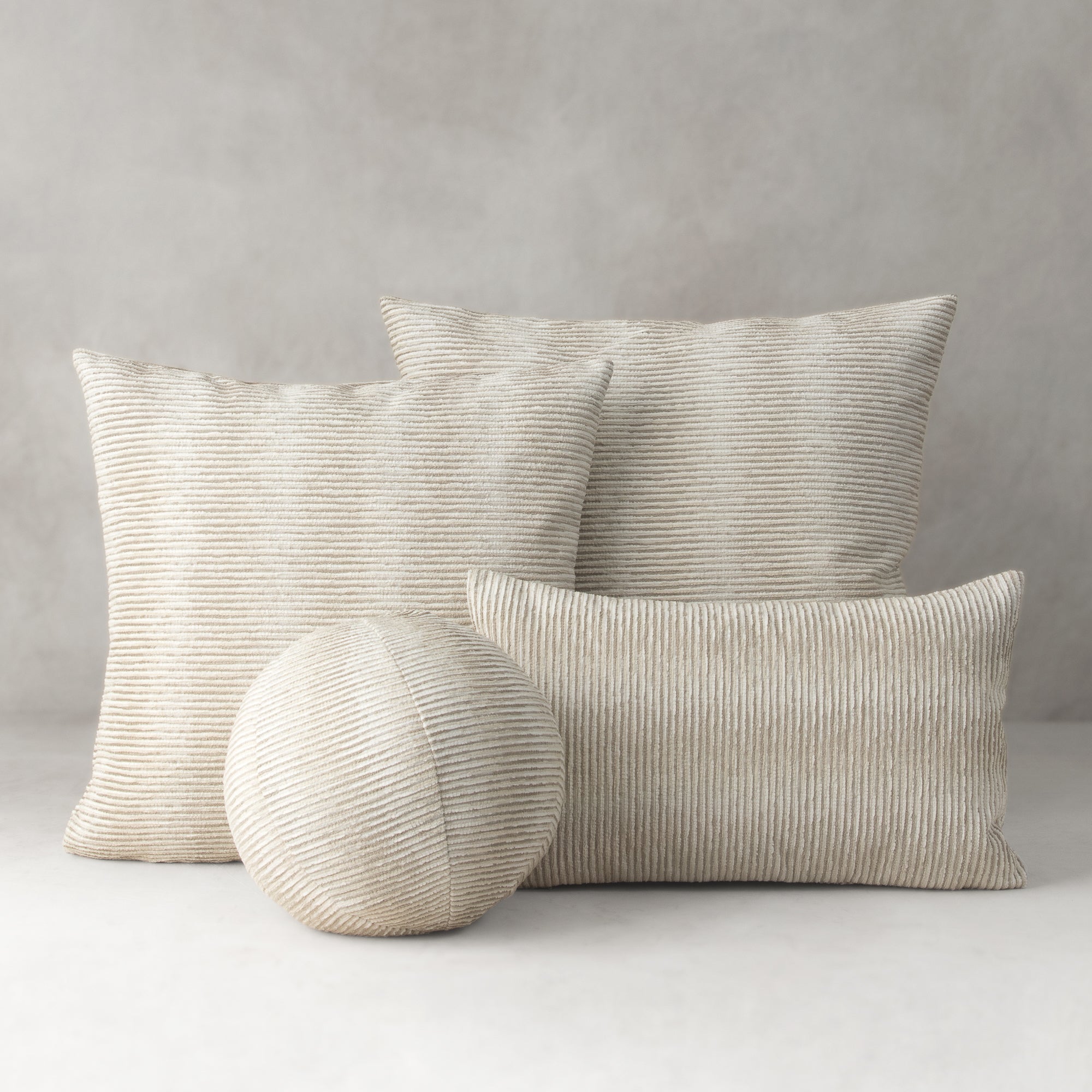 Set of textured pillows and a ball on a neutral background