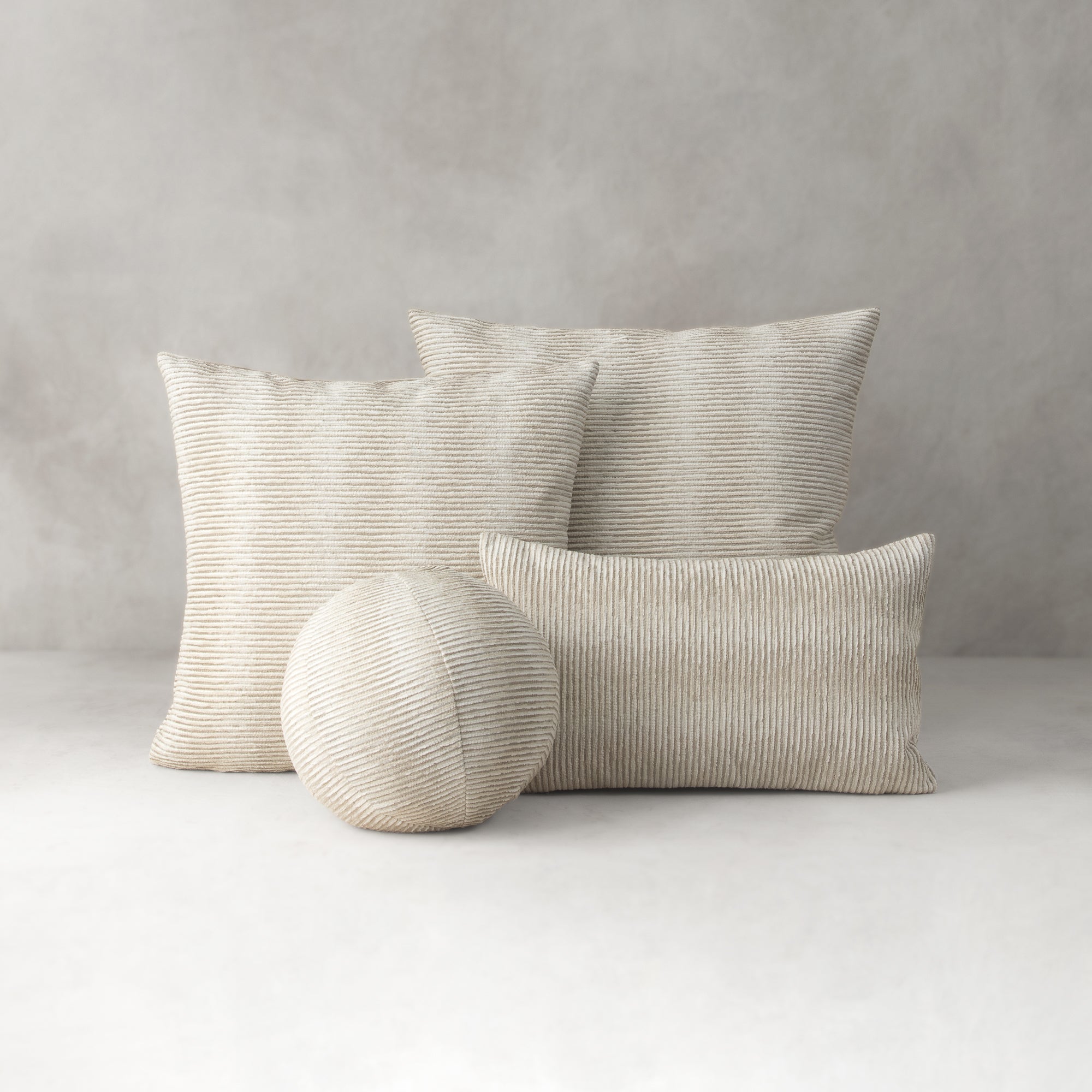Set of textured pillows and a ball on a neutral background