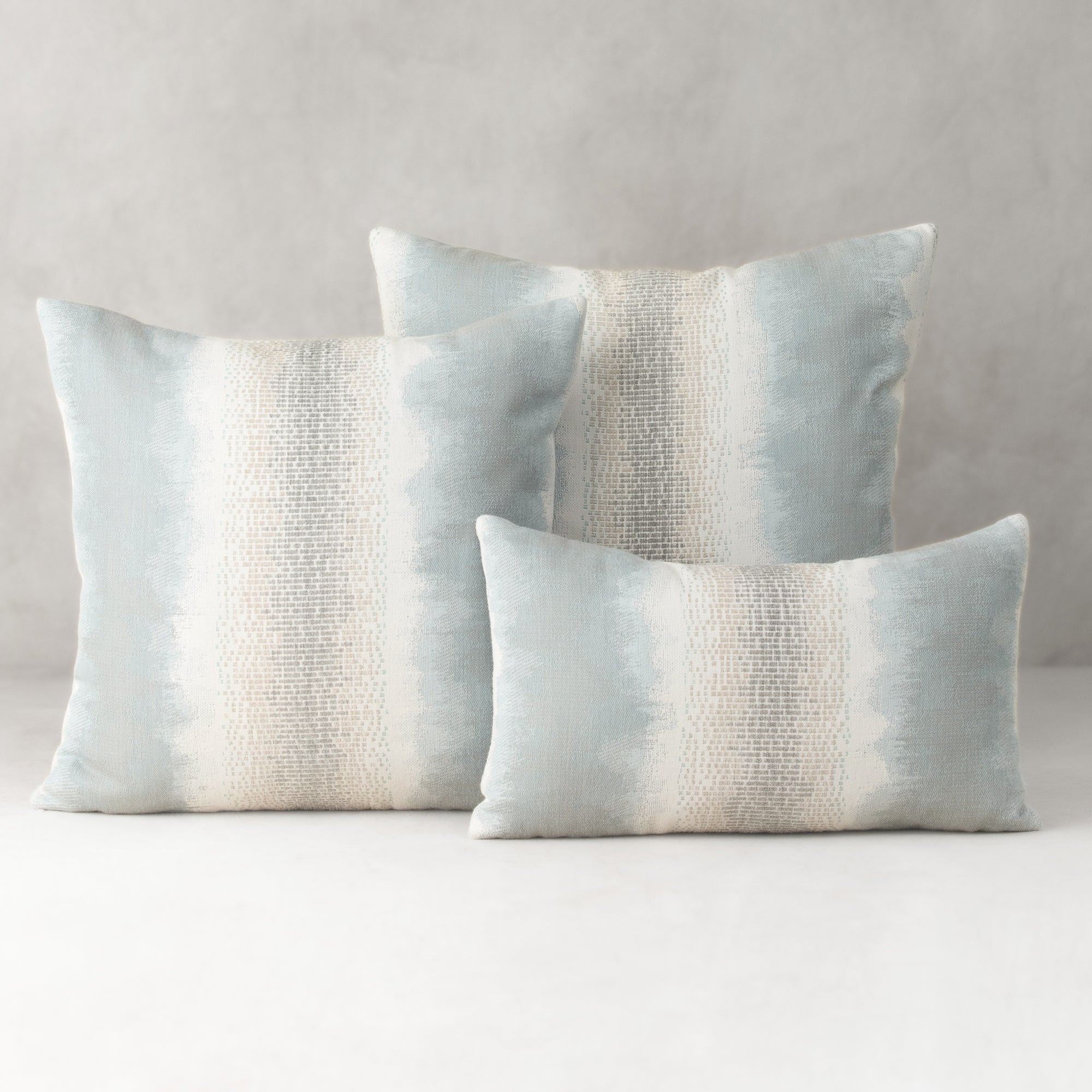 Three decorative pillows with a gradient pattern on a neutral background