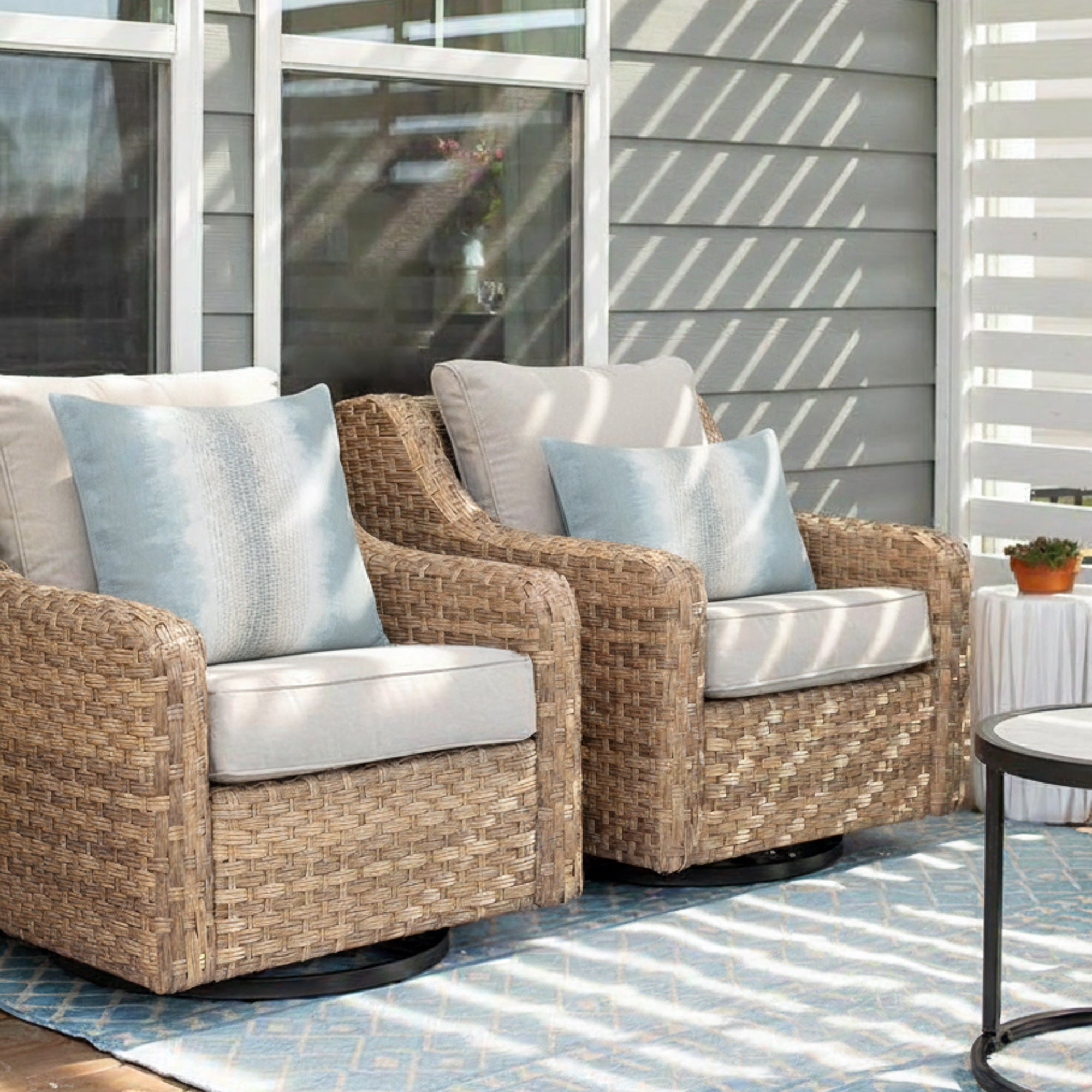 Outdoor safe ombre striped pillows in light blue and white on modern wicker outdoor chairs