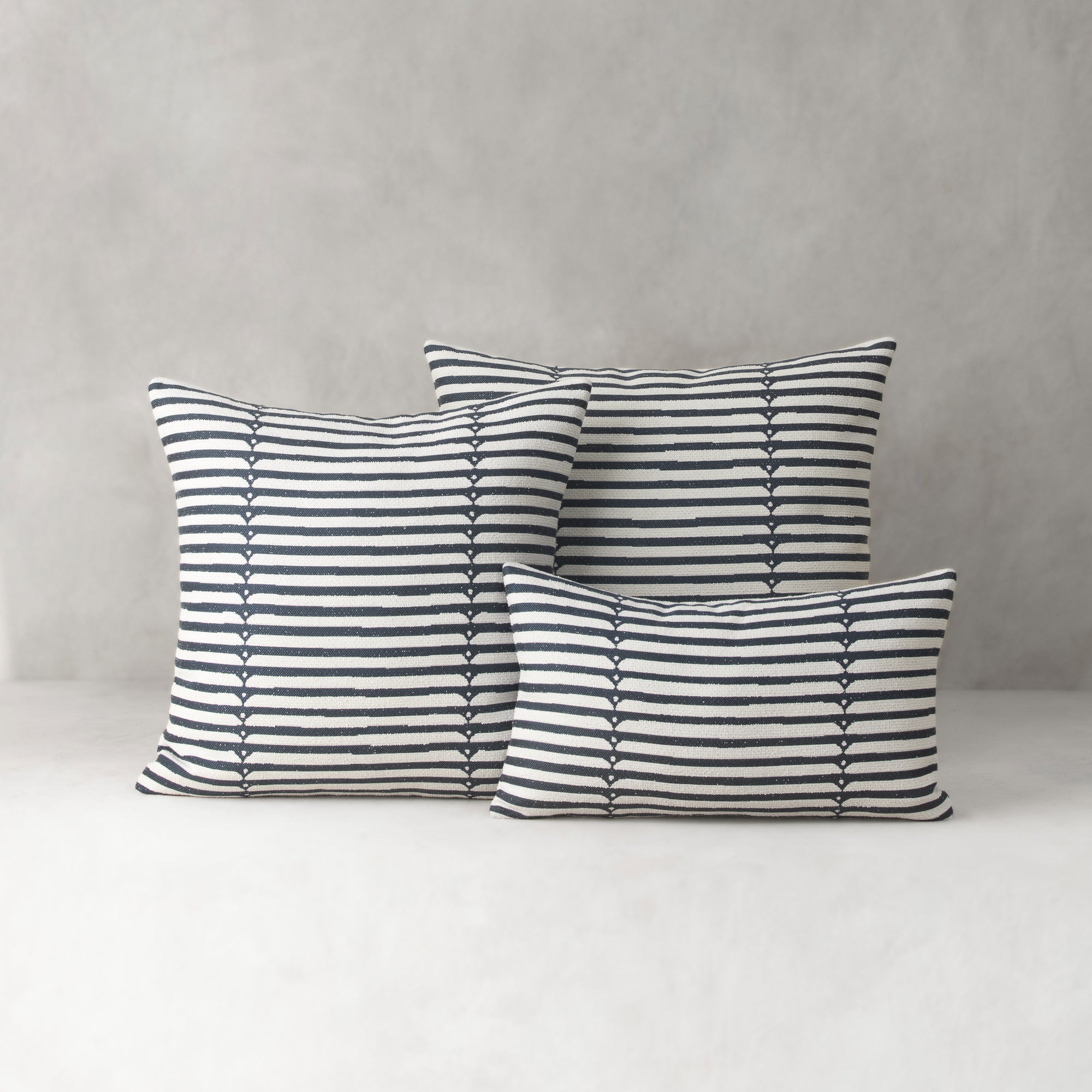 Set of three striped pillows on a neutral background