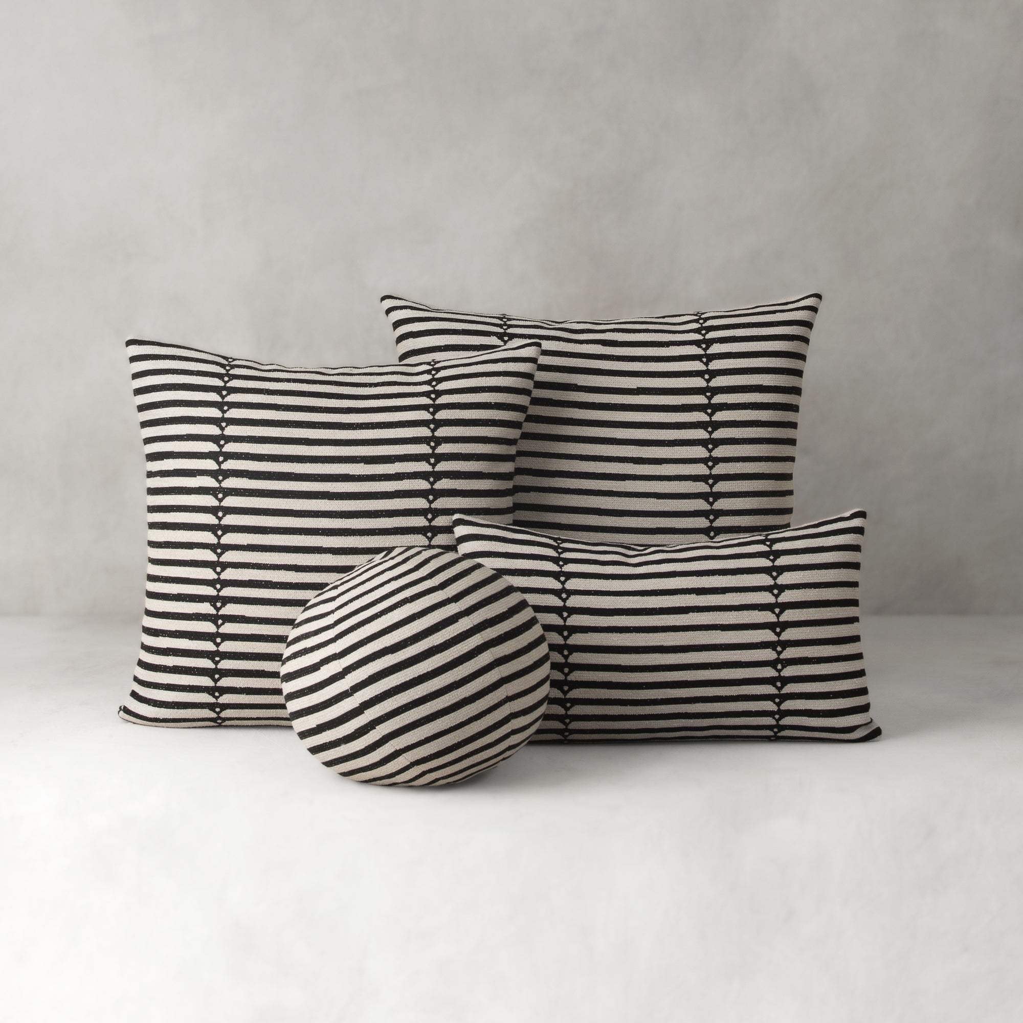 Set of black and white striped cushions on a neutral background