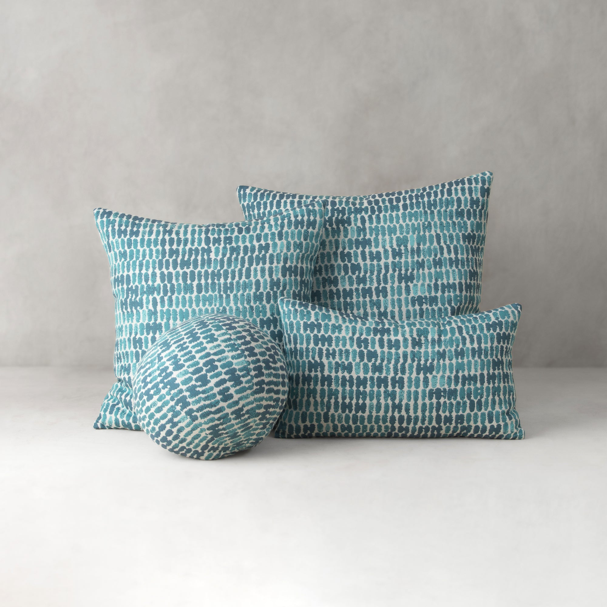 Set of four blue patterned pillows on a white surface with a gray background