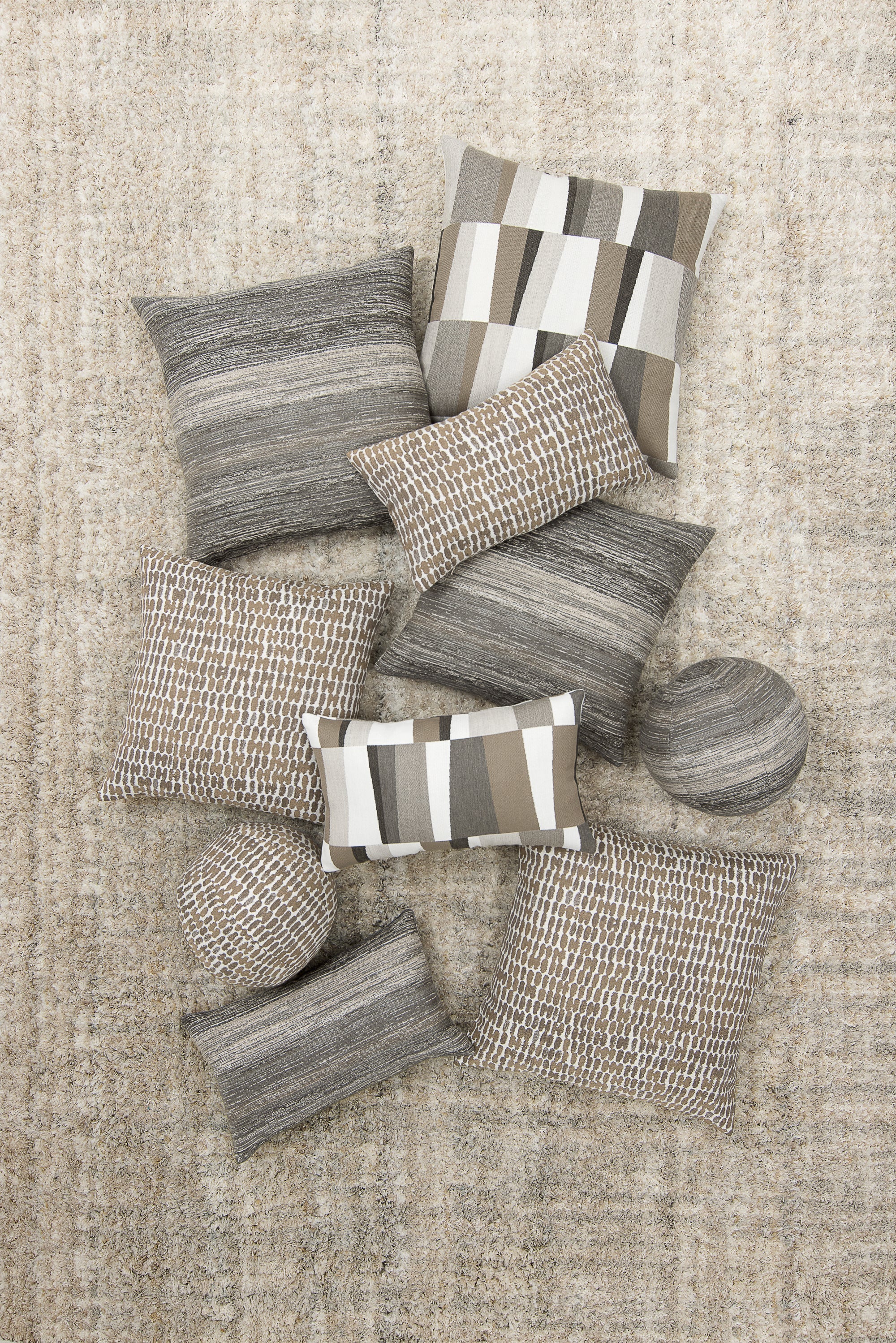Collection of gray and beige textured pillows on a neutral background
