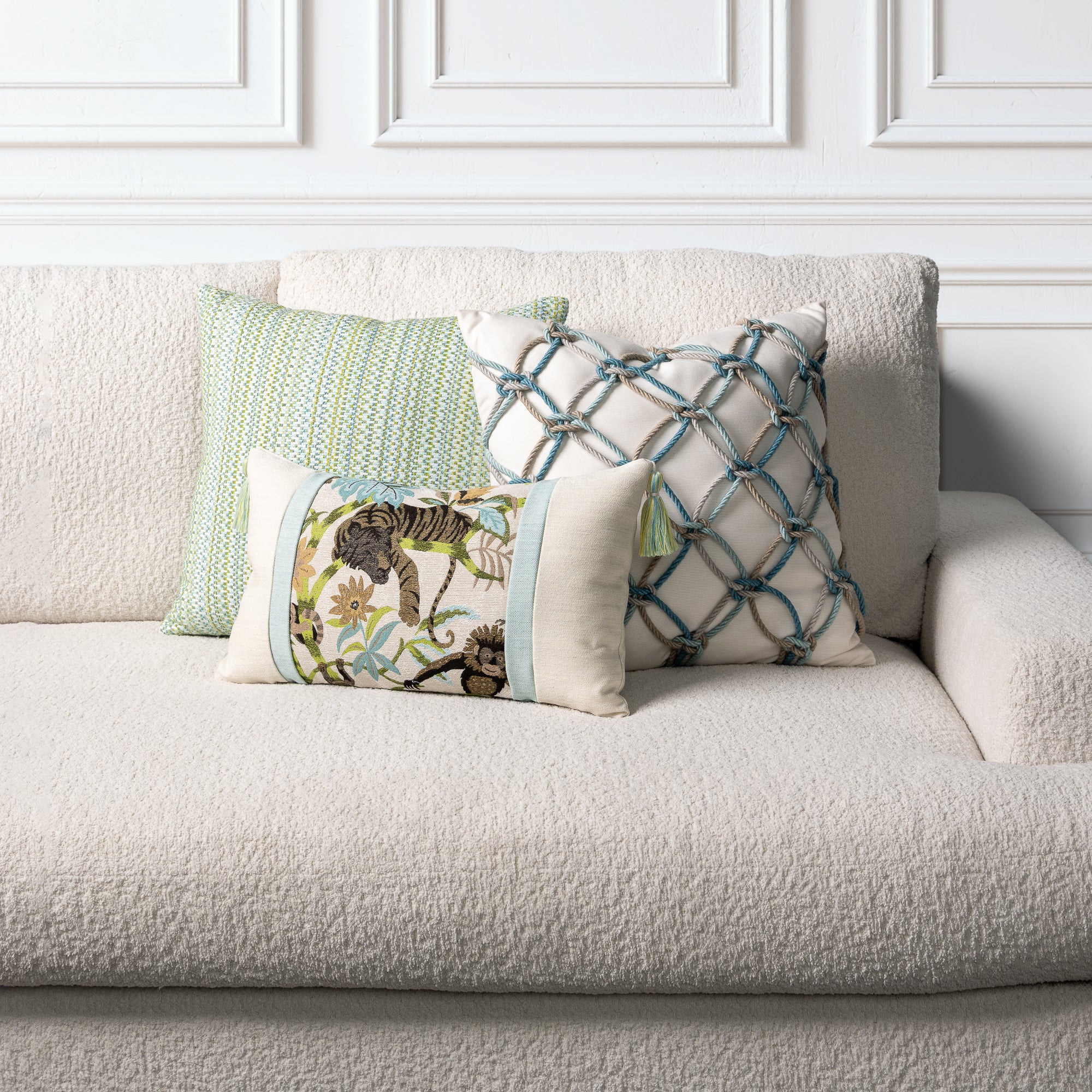 Decorative outdoor safe pillows on a beige sofa against a white paneled wall.