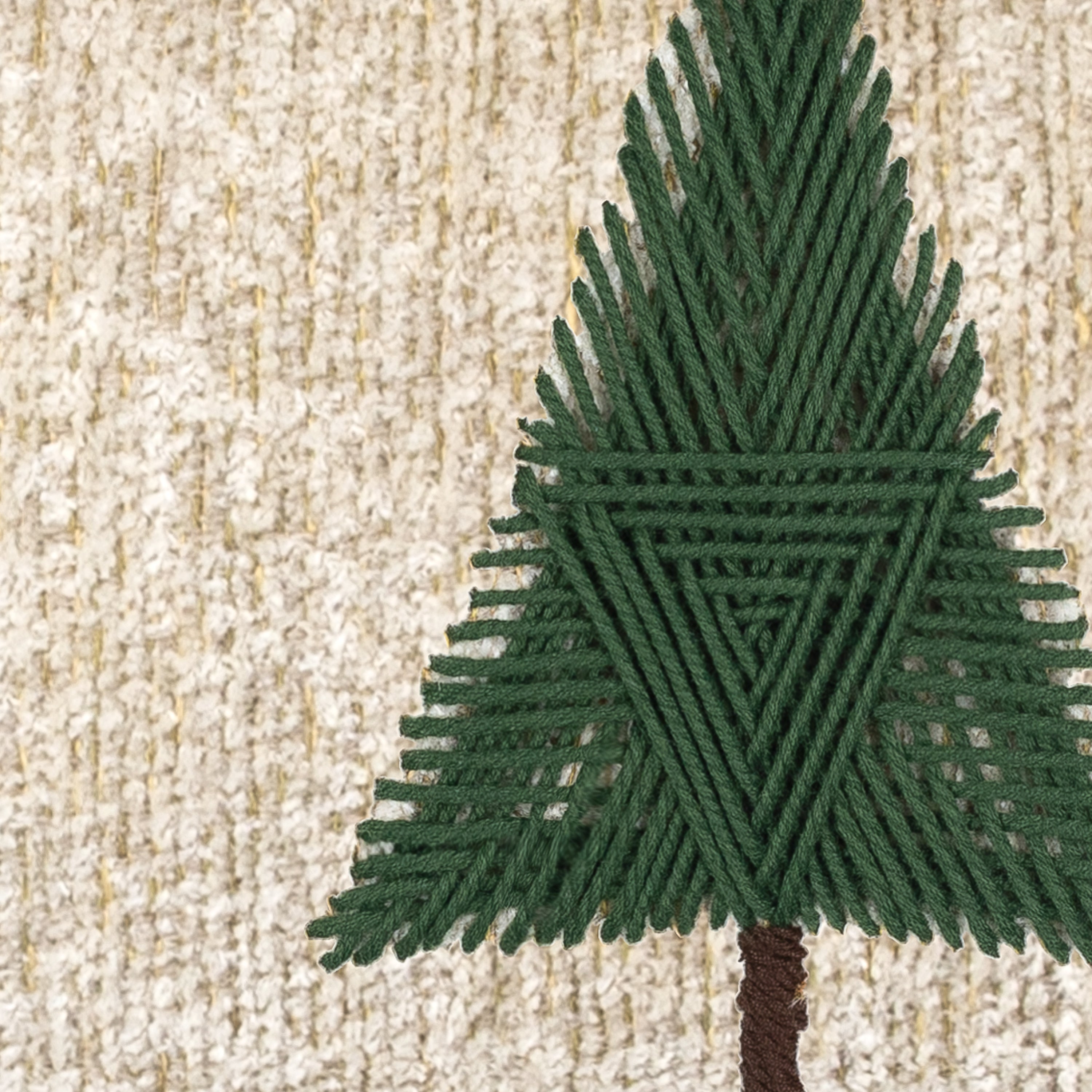 Detail image of Ivory outdoor pillow with holiday tree hand sewn detail for chic outdoor decor
